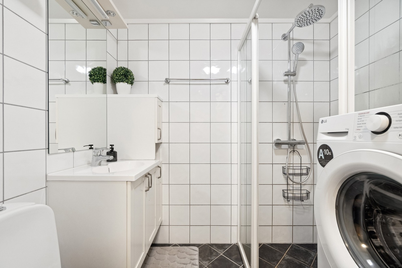 Pent bad med WC, lys innredning, dusjhjørne og opplegg for vaskemaskin. Galleribilde