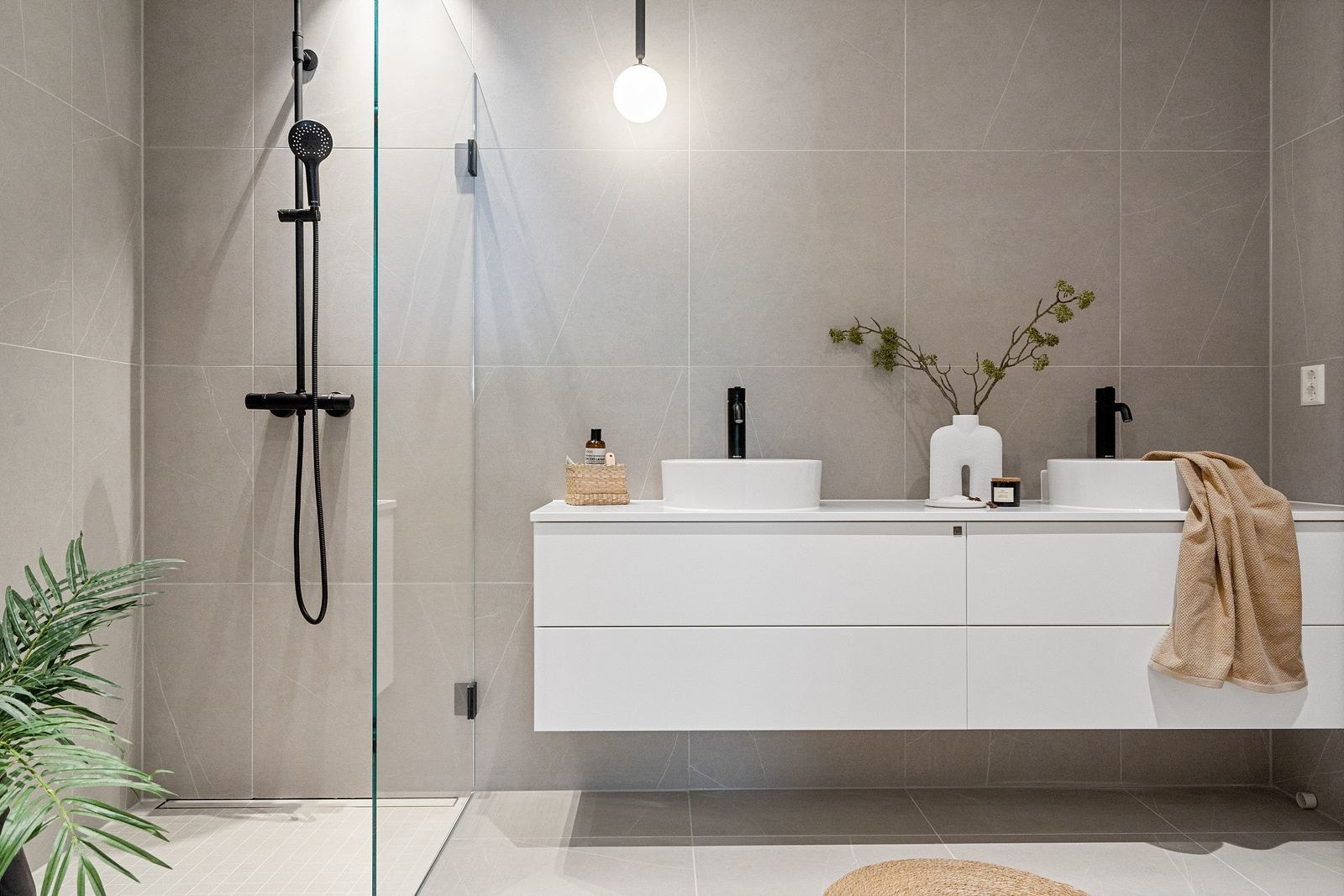 Det lekre badet har eksklusiv stil med grå fliser og sorte detaljer på innredningen. Galleribilde