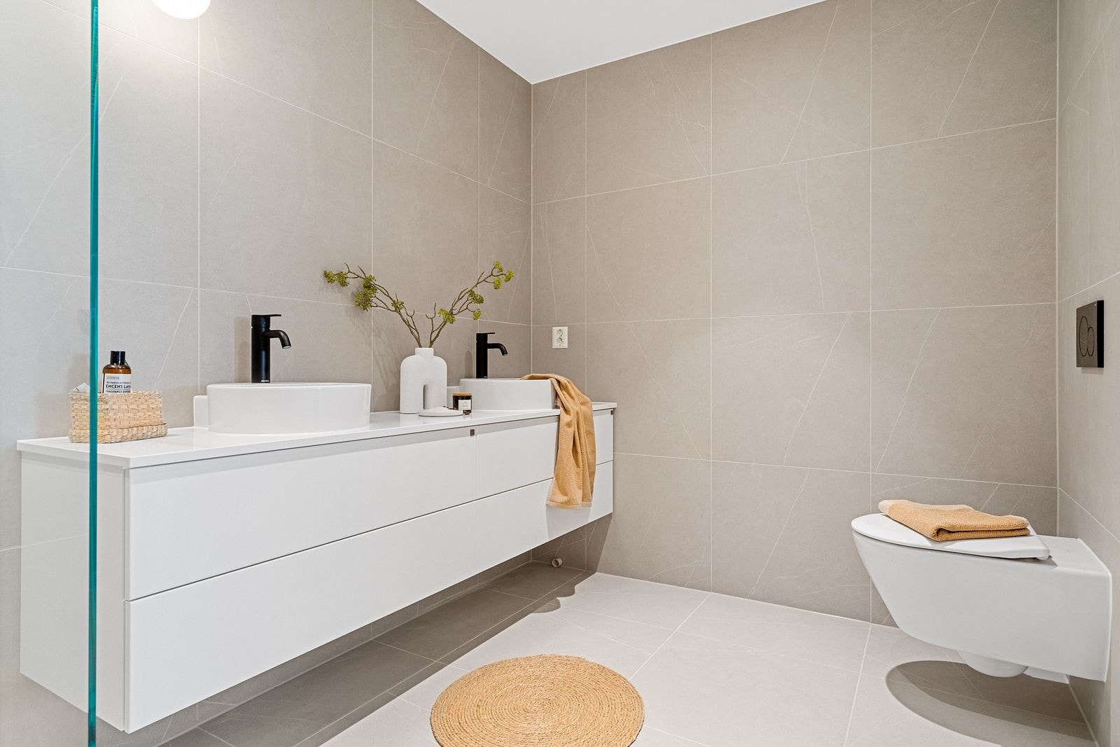 Badet er innredet med dobbel servant med underskap, dusjvegg i glass og vegghengt toalett. Galleribilde