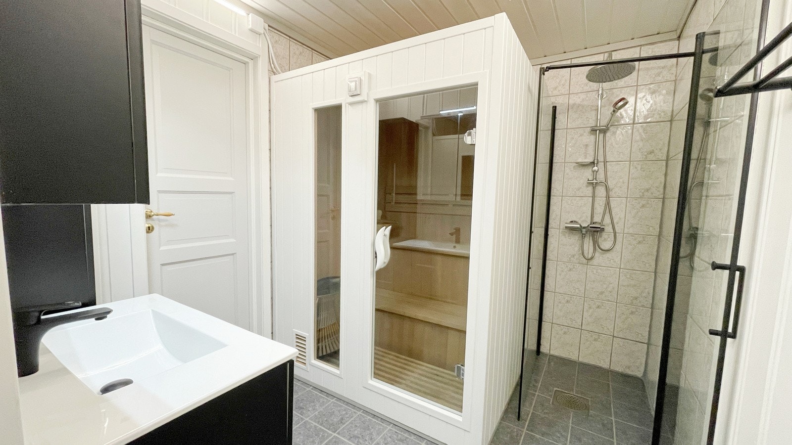 Badet har dusj på vegg, servant med skapinnredning og en badstue Galleribilde