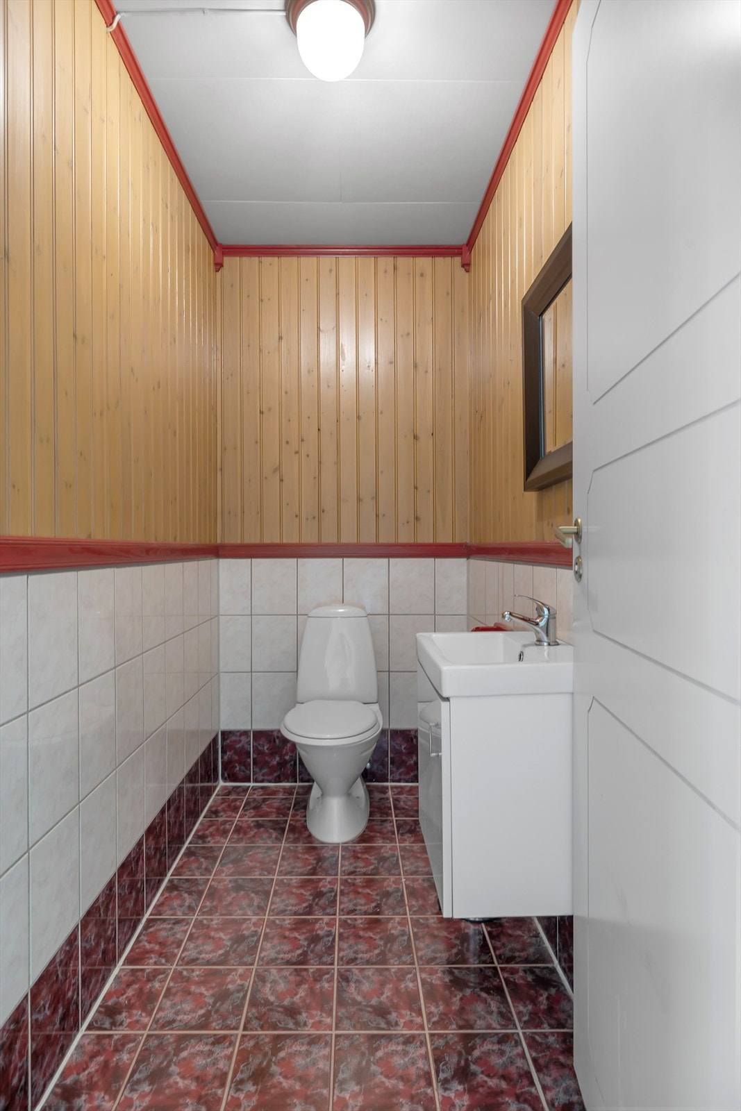 Separat toalettrom med gulvstående toalett og innredning med over og underskap. Galleribilde