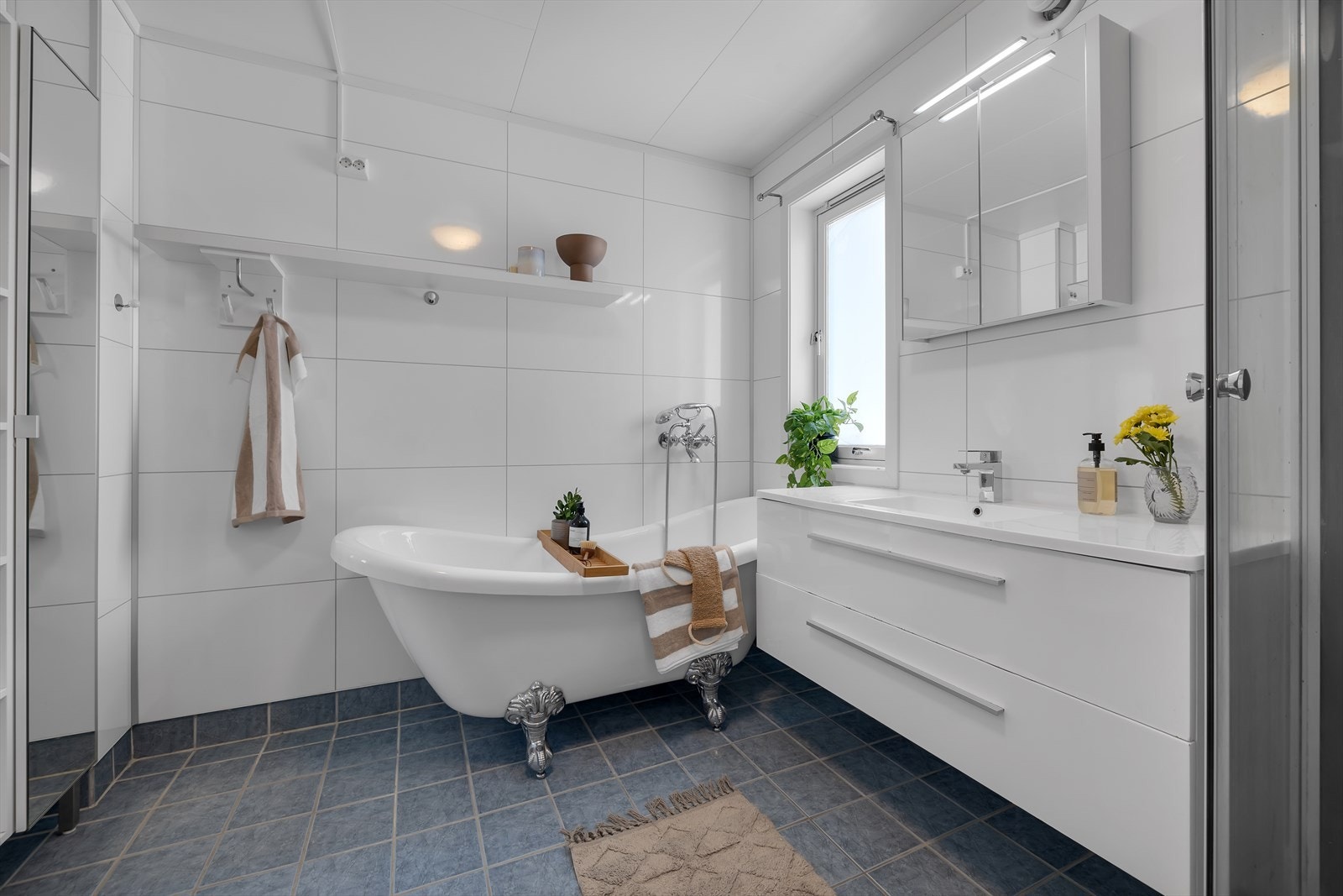 Bad i 1.etasje har flis på gulv og plater på vegg. Badekar og dusjkabinett. Galleribilde