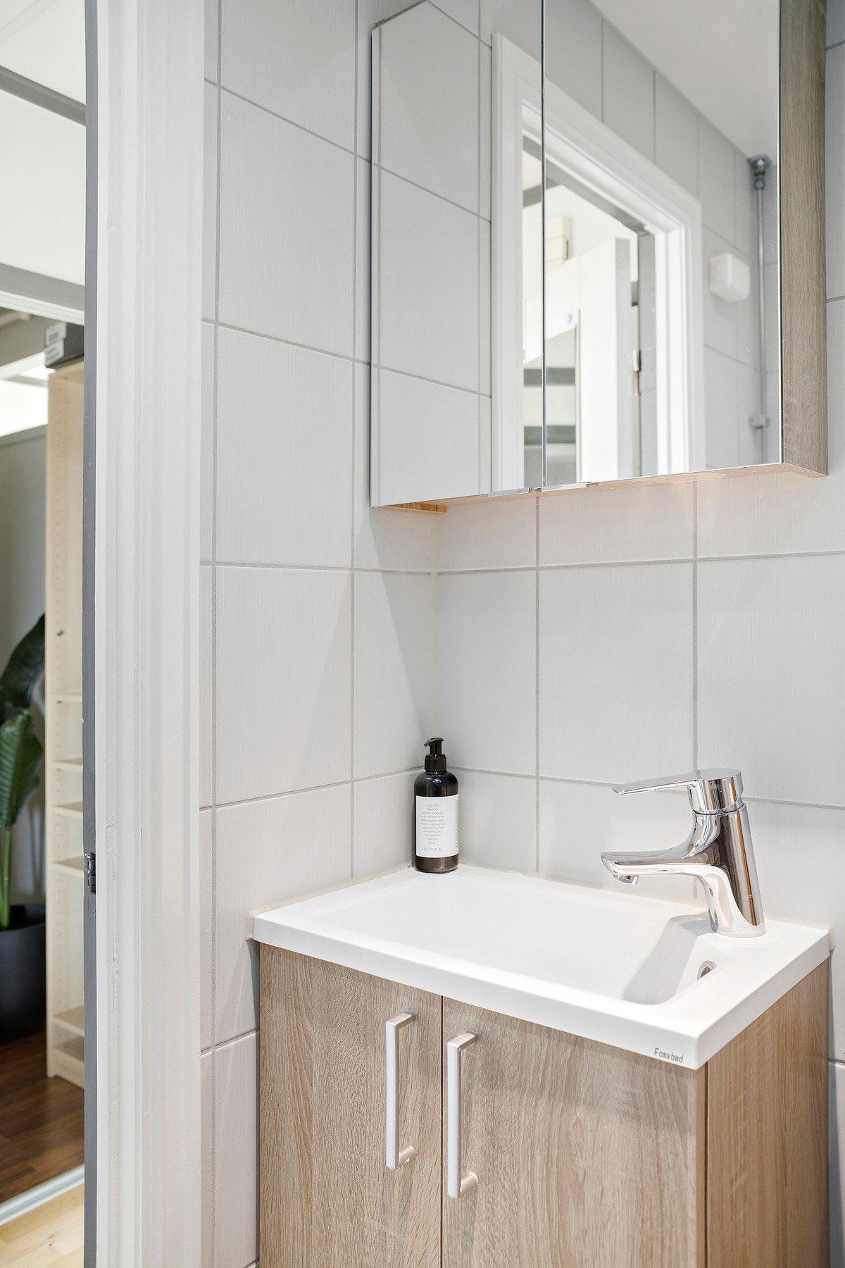 Badet er utstyrt med vegghengt servantskap med glatte fronter og nedsenket servant med armatur. Det er vegghengt speilskap og dusjhørne med innfellbare glassdører og dusjarmatur tilkoblet hånddusj. Det er også vegghengt toalett. Galleribilde