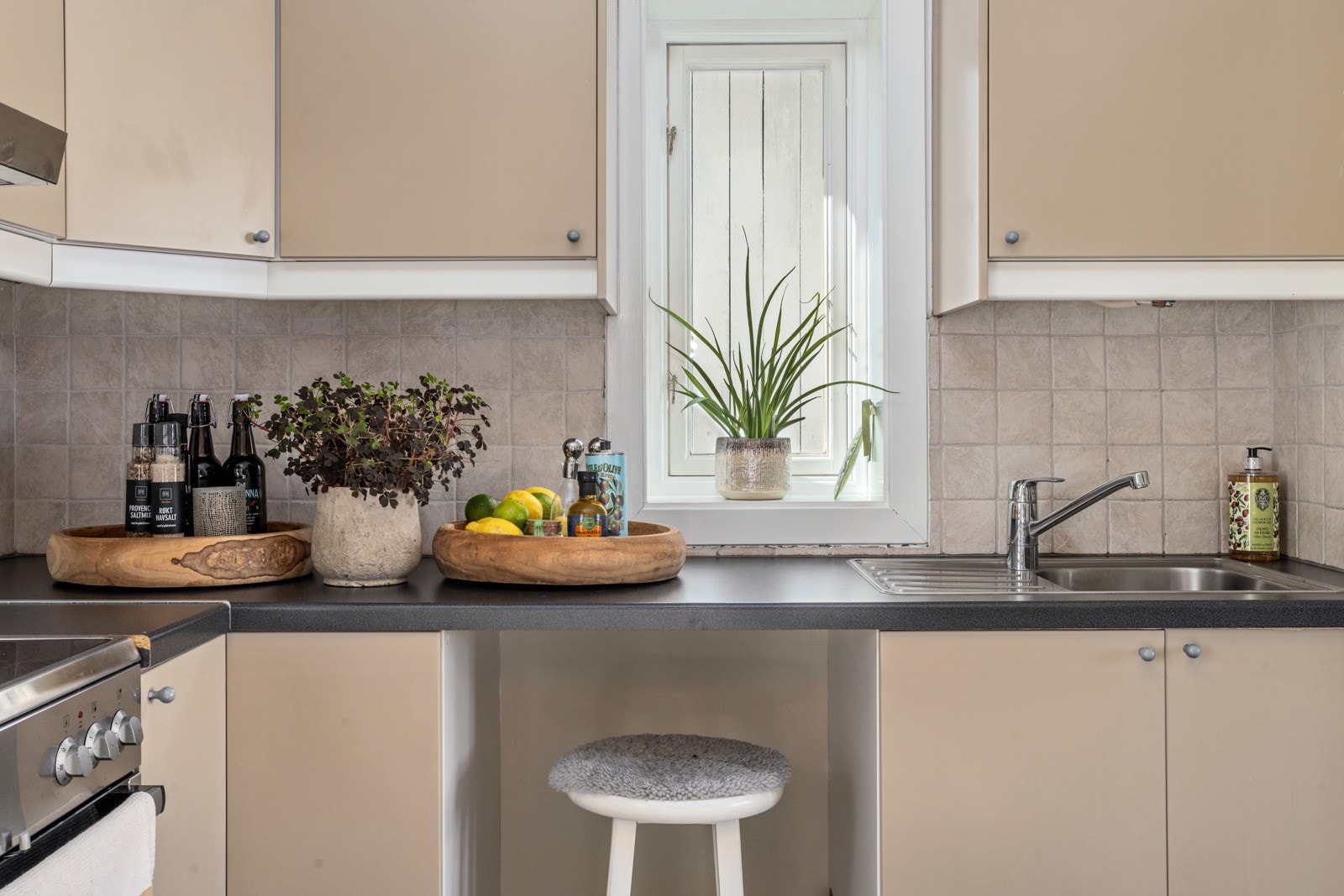 Kjøkkenet har innredning med glatte, malte fronter, laminat benkeplate med rustfri kum og fliser over benken. Ventilator over kokesonen. Galleribilde