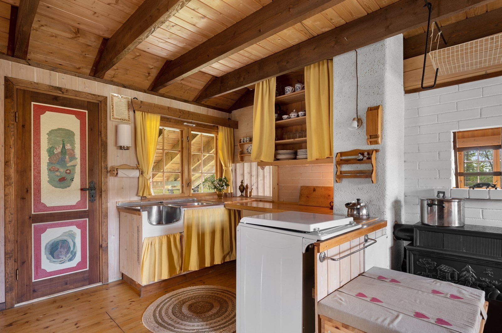 Kjøkkenet har sjarmerende forheng til kjøkkenskapene som gir en ekstra lun følelse. Rommet har også et matskap med håndmalt dør og mange hylle seksjoner. Galleribilde