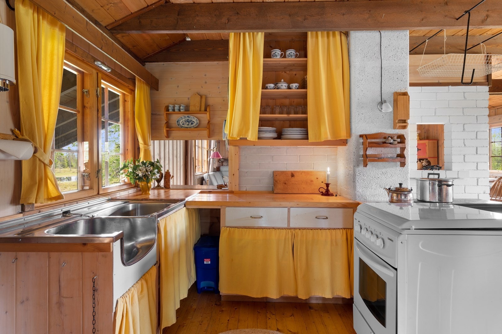 Innredningen er utført i heltre, og kombinerer over- og underskap med praktiske skuffer for oppbevaring. Benkeplaten av heltre med en en enkel og funksjonell utslagsvask med avløp til terreng. Gasskomfyr har mulighet for gasstank i benk ved siden av. Galleribilde