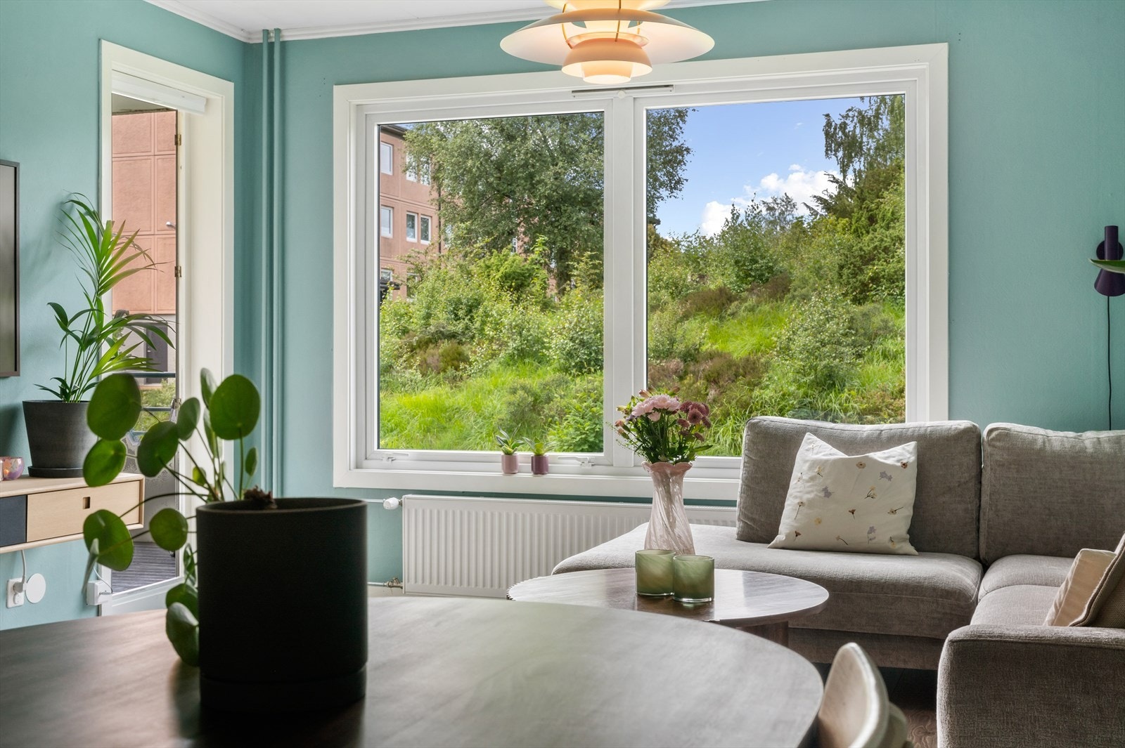 Lys og luftig stue med store vinduer som gir flott utsikt til grønne omgivelser. Perfekt for avslapning og hygge. Galleribilde
