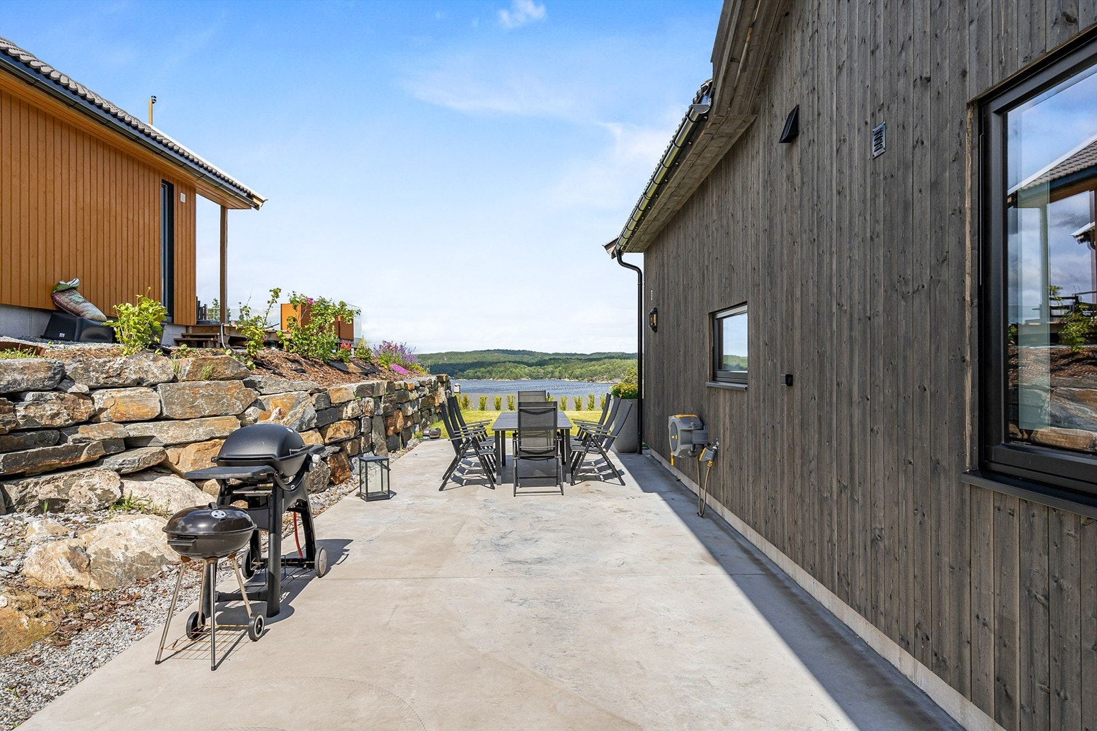 Del av terrassen med ettermiddagssol. Flott utsikt. Utvendig vann. Galleribilde