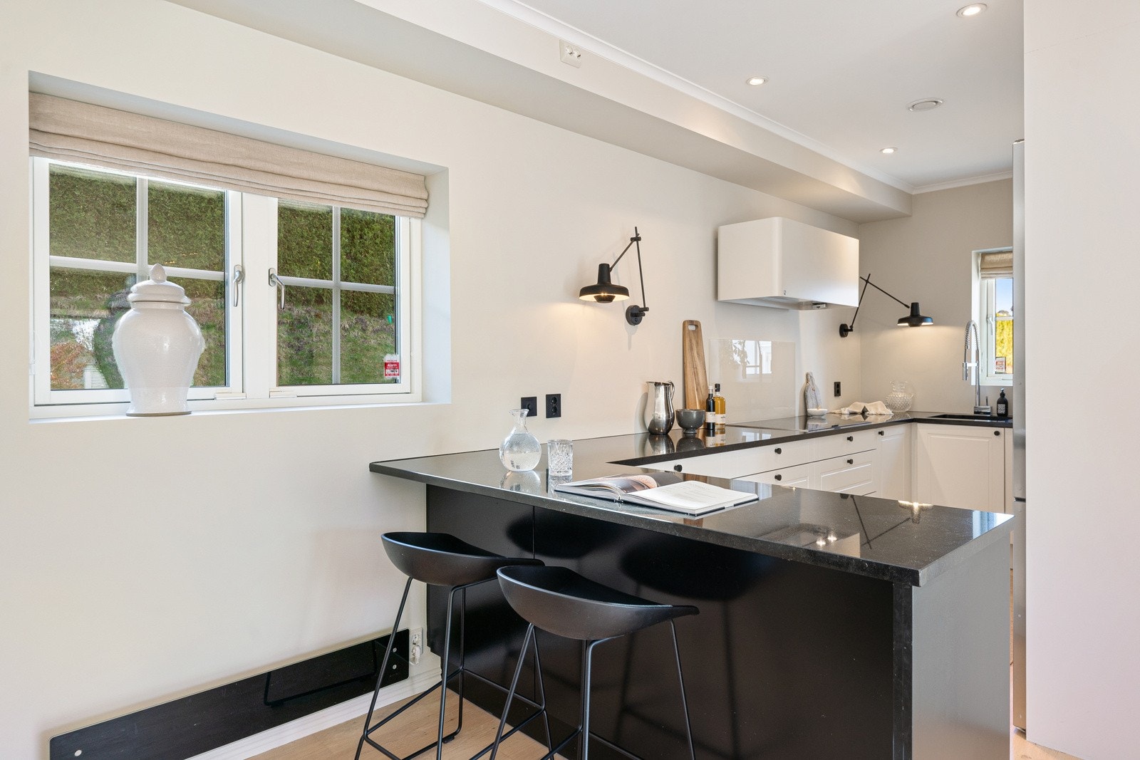 Lekkert og stilsikkert kjøkken fra HTH med rikelig med skap- og benkeplass, samt barløsning med plass til to stoler Galleribilde