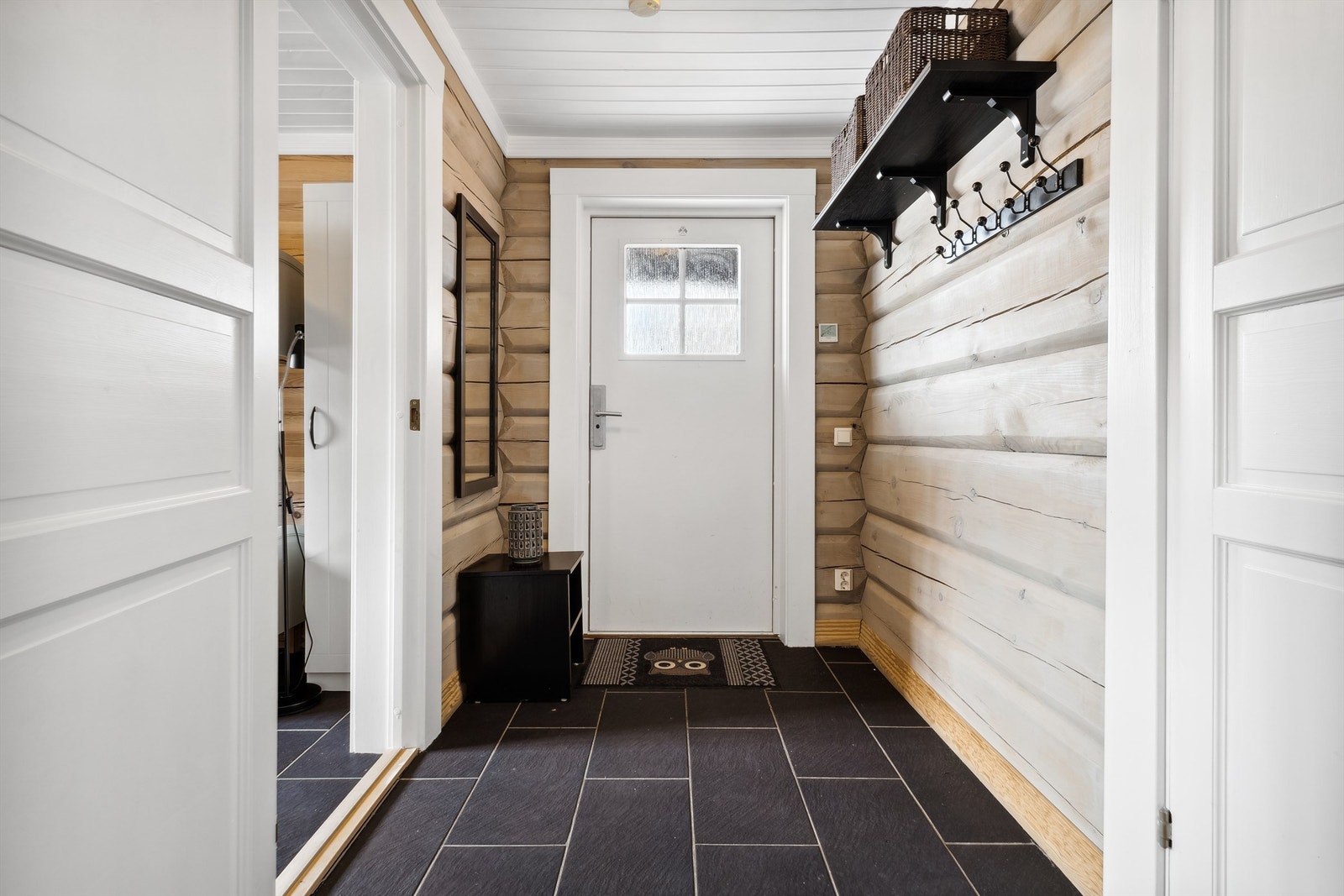 Lys og innbydende entré med elegante, mørke fliser og naturlig treverk. Galleribilde