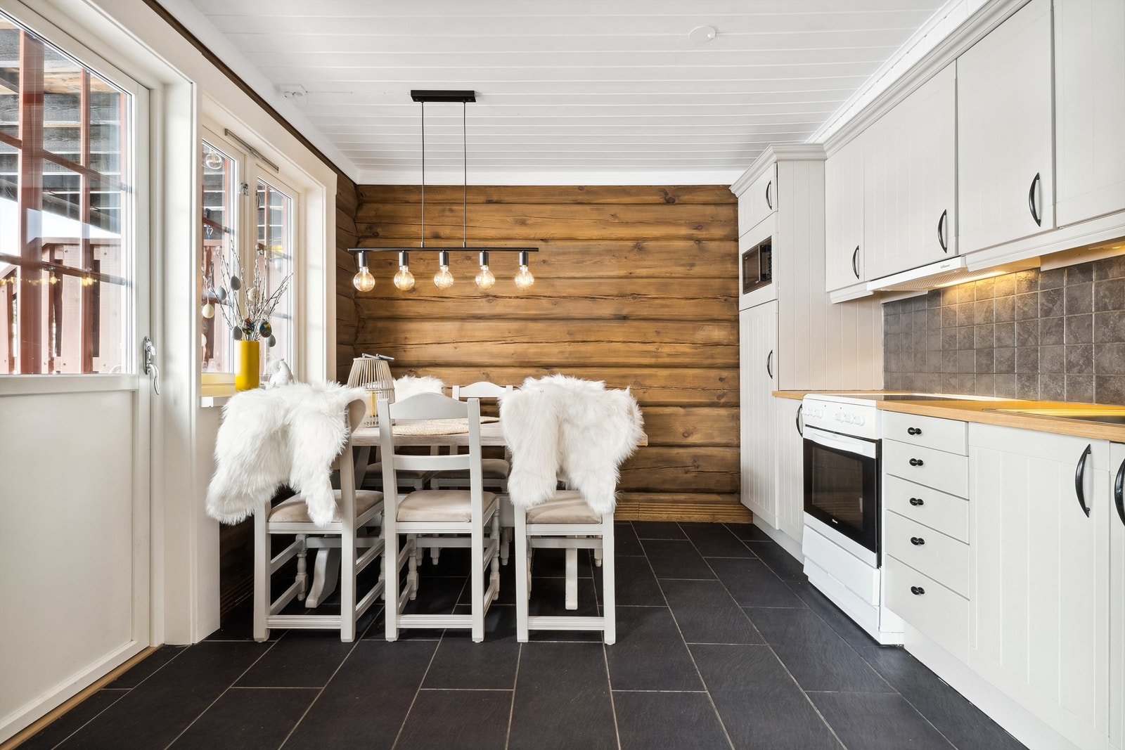 Kjøkken med takhøy innredning som har godt med skap og benkeplass. Galleribilde