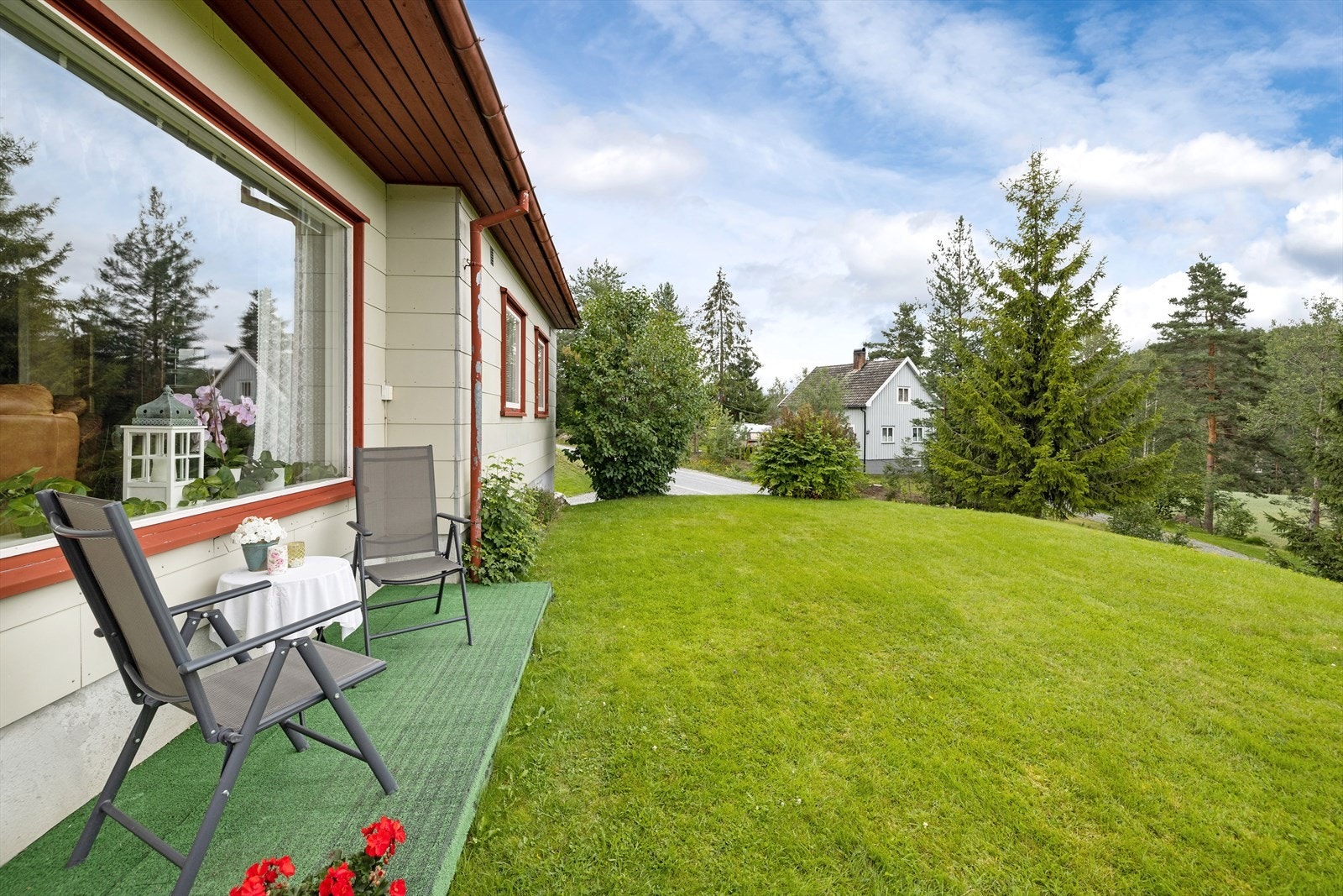 Tomten er opparbeidet med plen, beplantning og gruset gårdsplass. Galleribilde