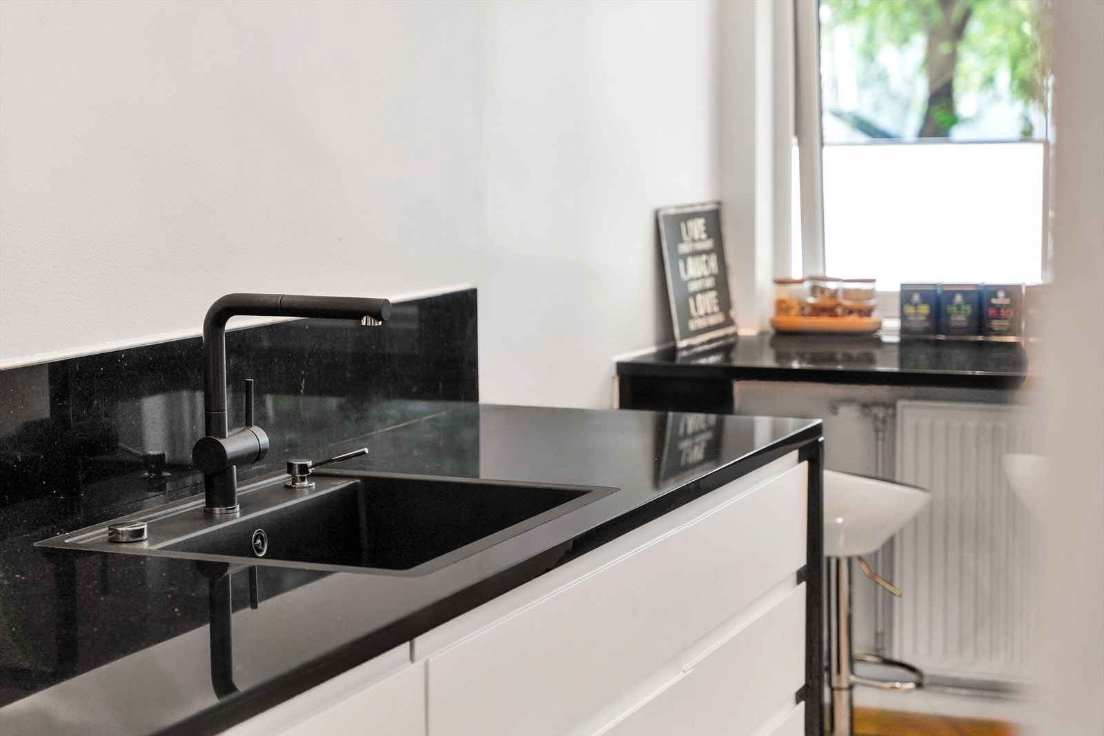 Her får du en lys og moderne kjøkkeninnredning fra IKEA med glatte fronter og steinbelagt benkeplate med planlimt oppvaskkum og ett-greps blandebatteri. Galleribilde