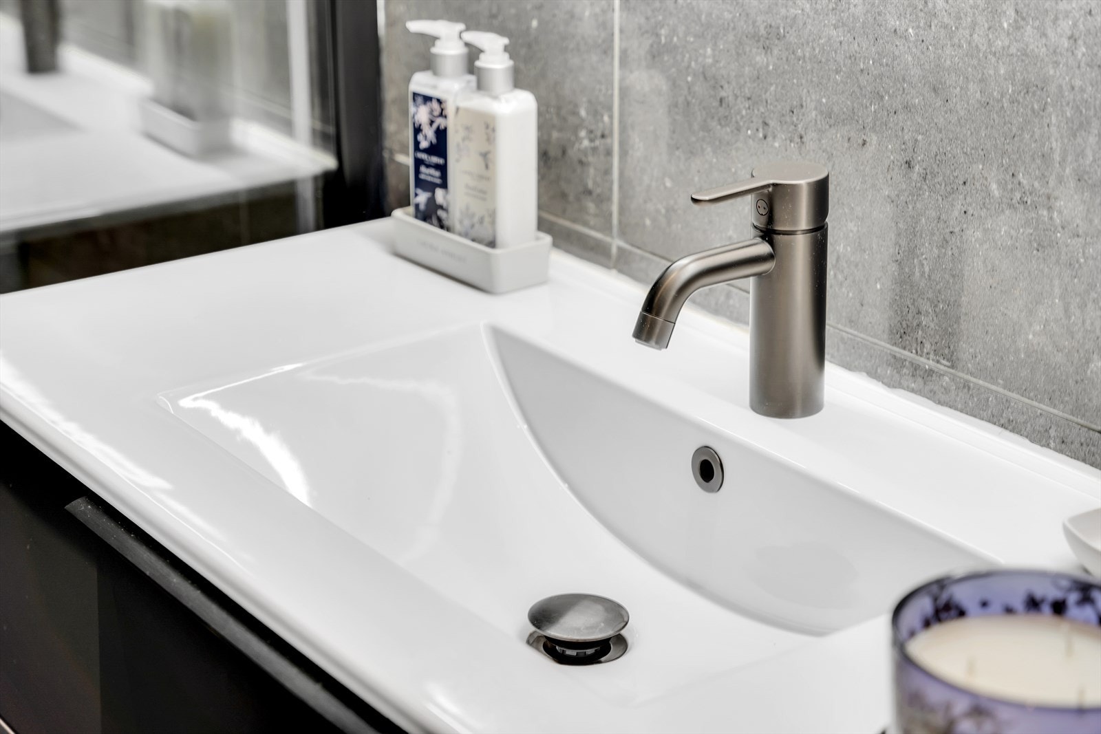 Baderomsinnredning fremstår med servant med underskap, speilskap med lys, håndkletørrer, veggmontert toalett, samt opplegg for vaskemaskin. Galleribilde