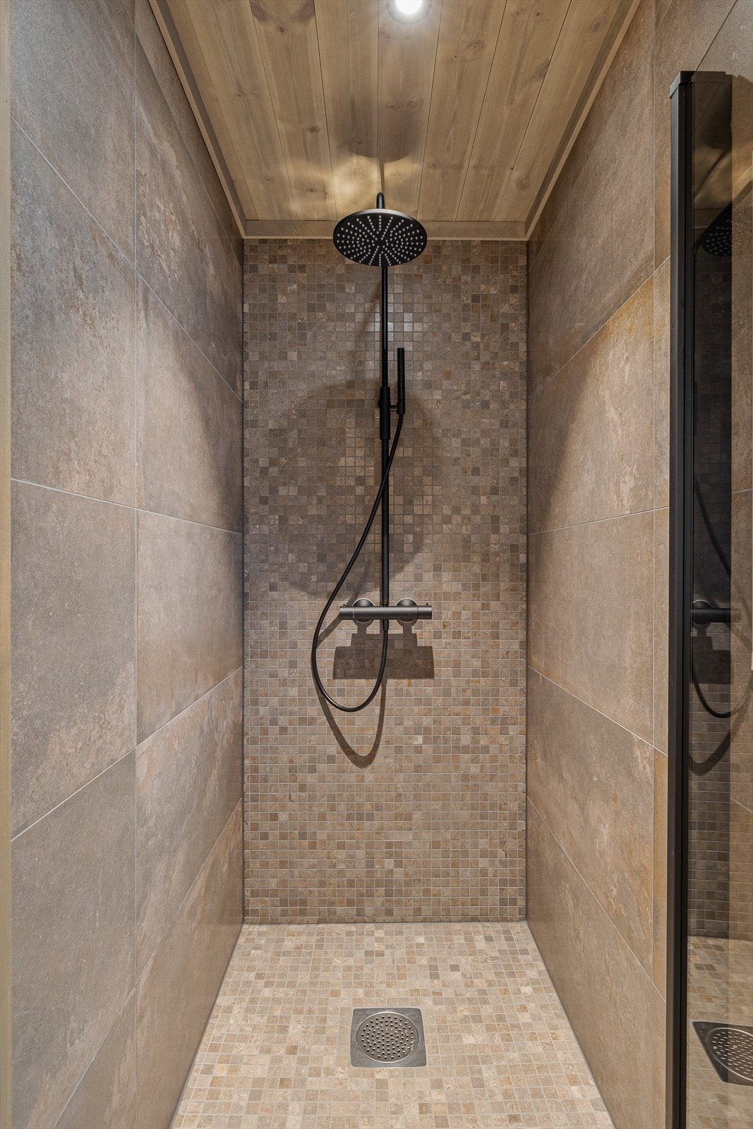 Hovedbadet har dusjhjørne med glassdør og sort dusjarmatur montert på vegg. Galleribilde