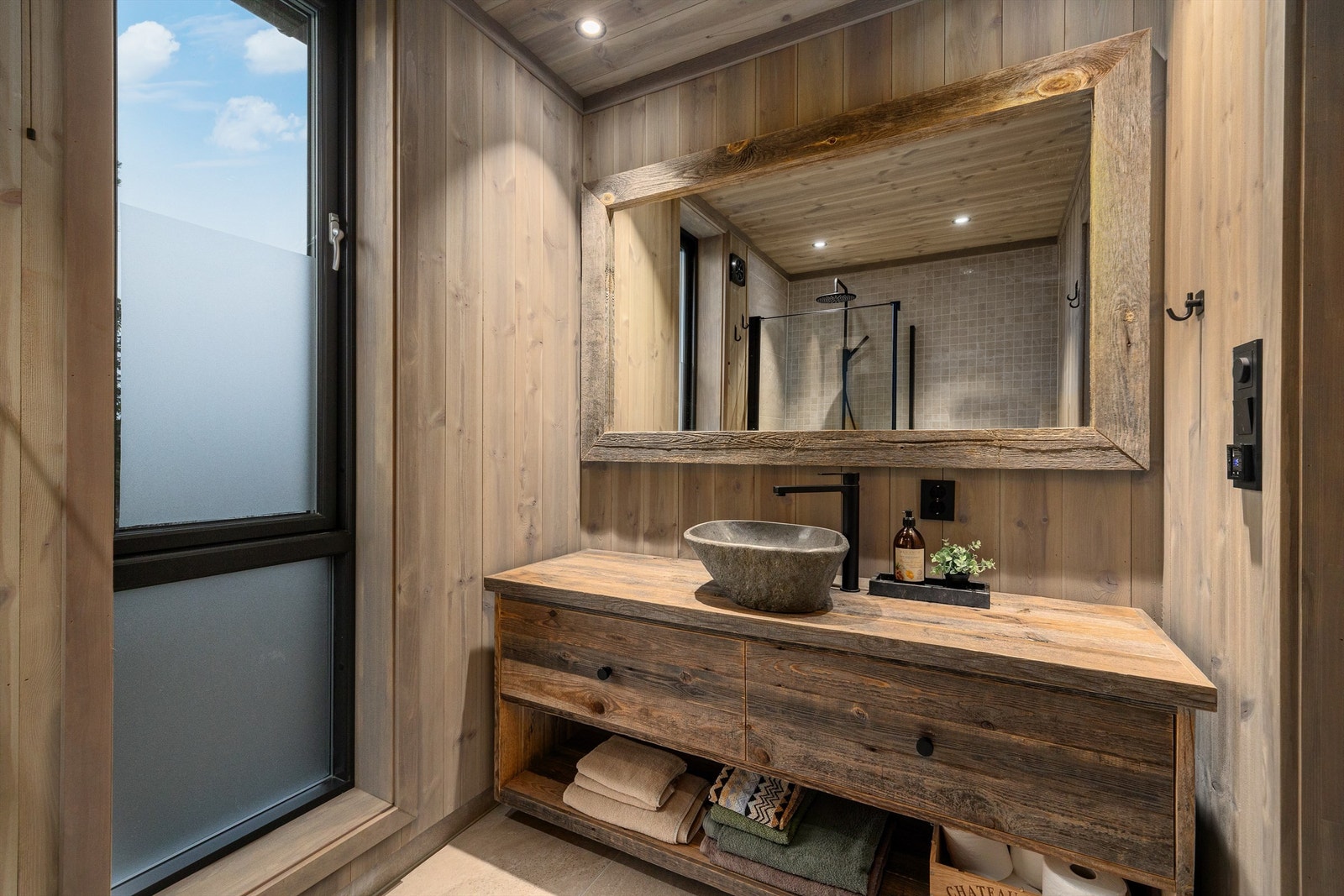 Det er flis på gulvet på begge badene, på vegger er det furu sprekkpanel og mosaikk/flis i dusjsonene og i himlingen er det behandlet panel med downlights. Galleribilde