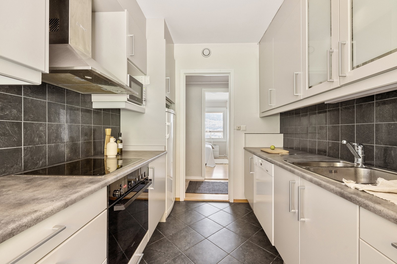 Kjøkkenet består av kjøkkeninnredning med slette fronter, ett glasskap og laminat benkeplate med nedfelt vask av stål. Galleribilde