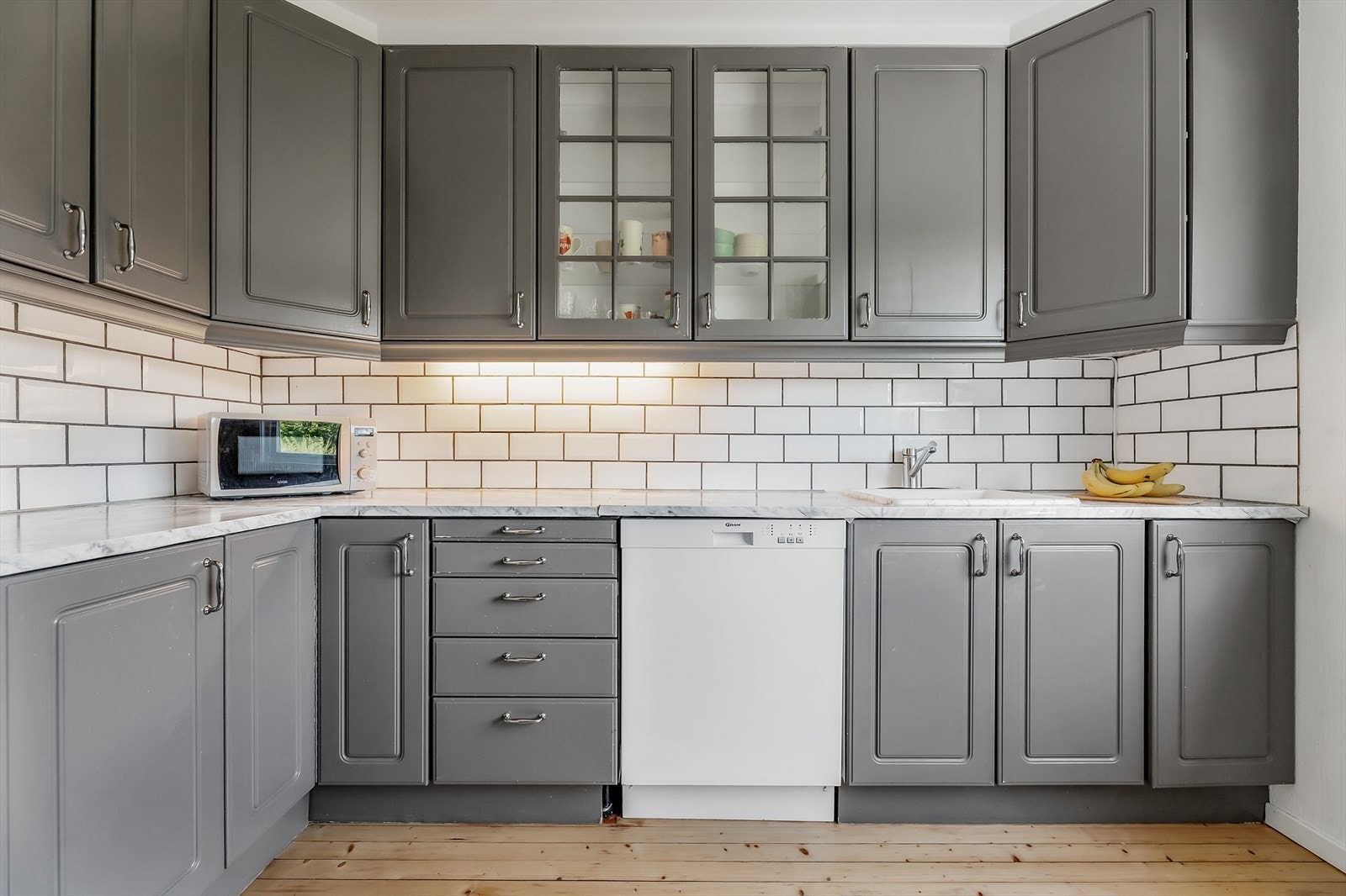 Innredningen har mørkmalte profilerte fronter, vitrineskap og laminerte benkeplater Galleribilde