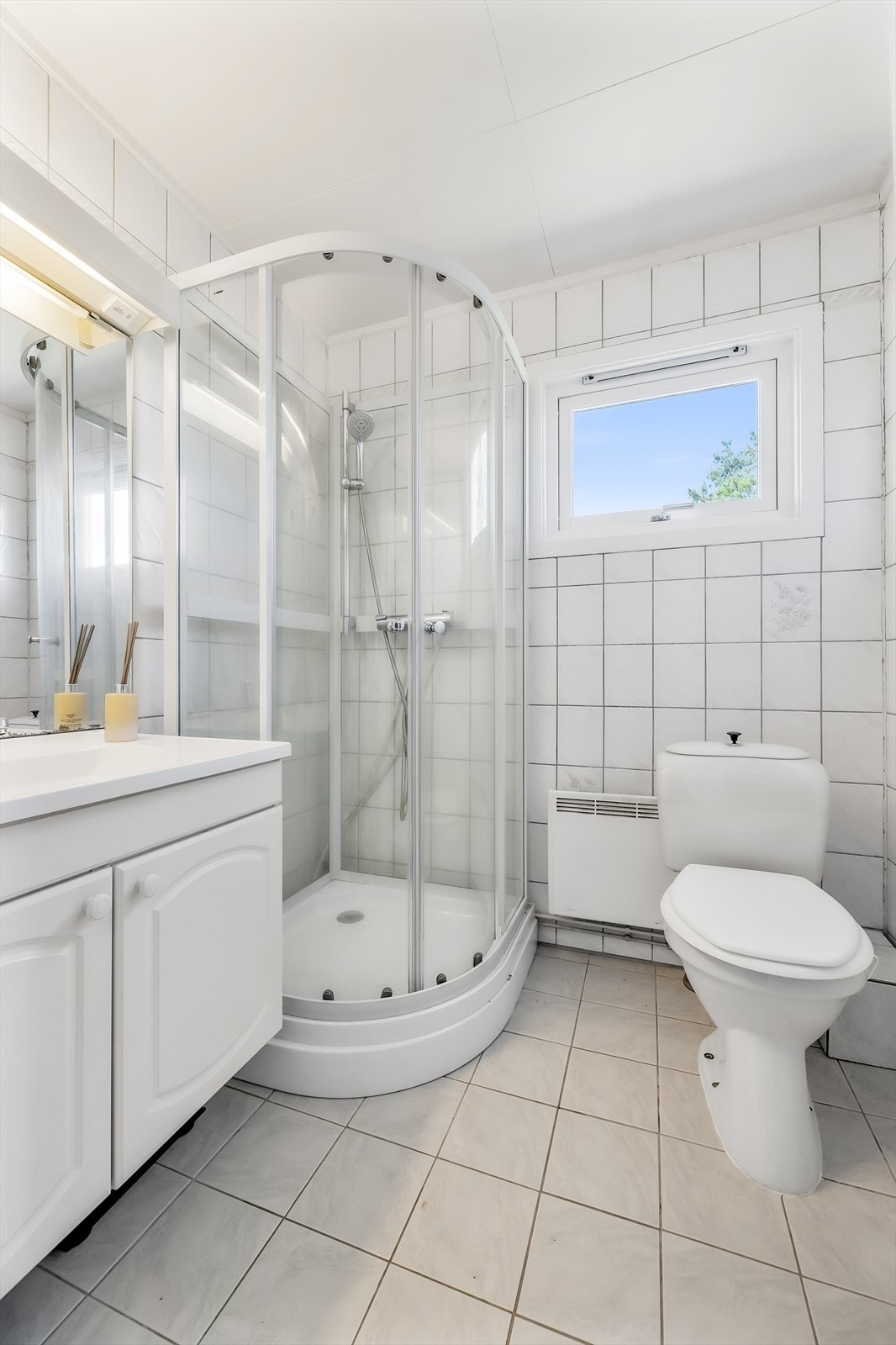 Flislagt bad med panelovn som oppvarming og vindu for naturlig lys Galleribilde