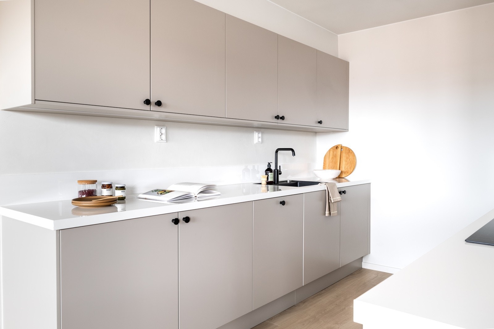 Malt flate og sprutplate mellom benkeplate og overskap samt benkeskapsbelysning og stikkontakter under overskap. Galleribilde