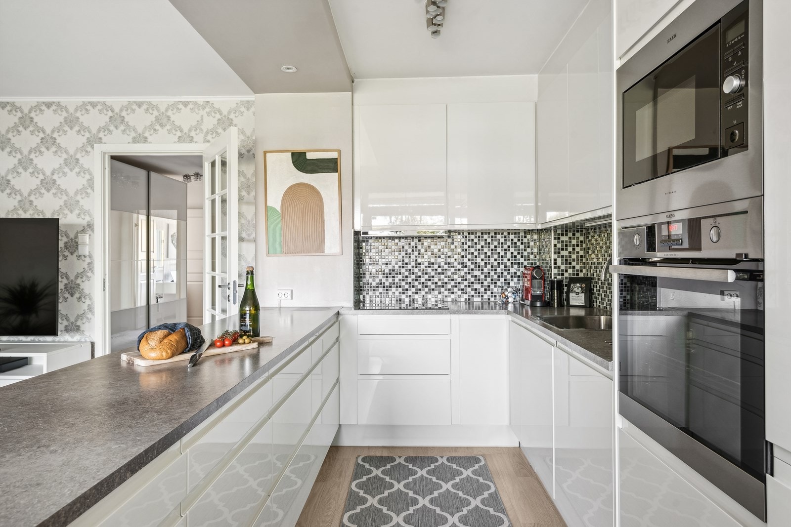 Kjøkkeninnredning type Norema med hvite glatte fronter i høyglans. Benkeplater i laminat, rustfri oppvaskkum og ventilator. Galleribilde