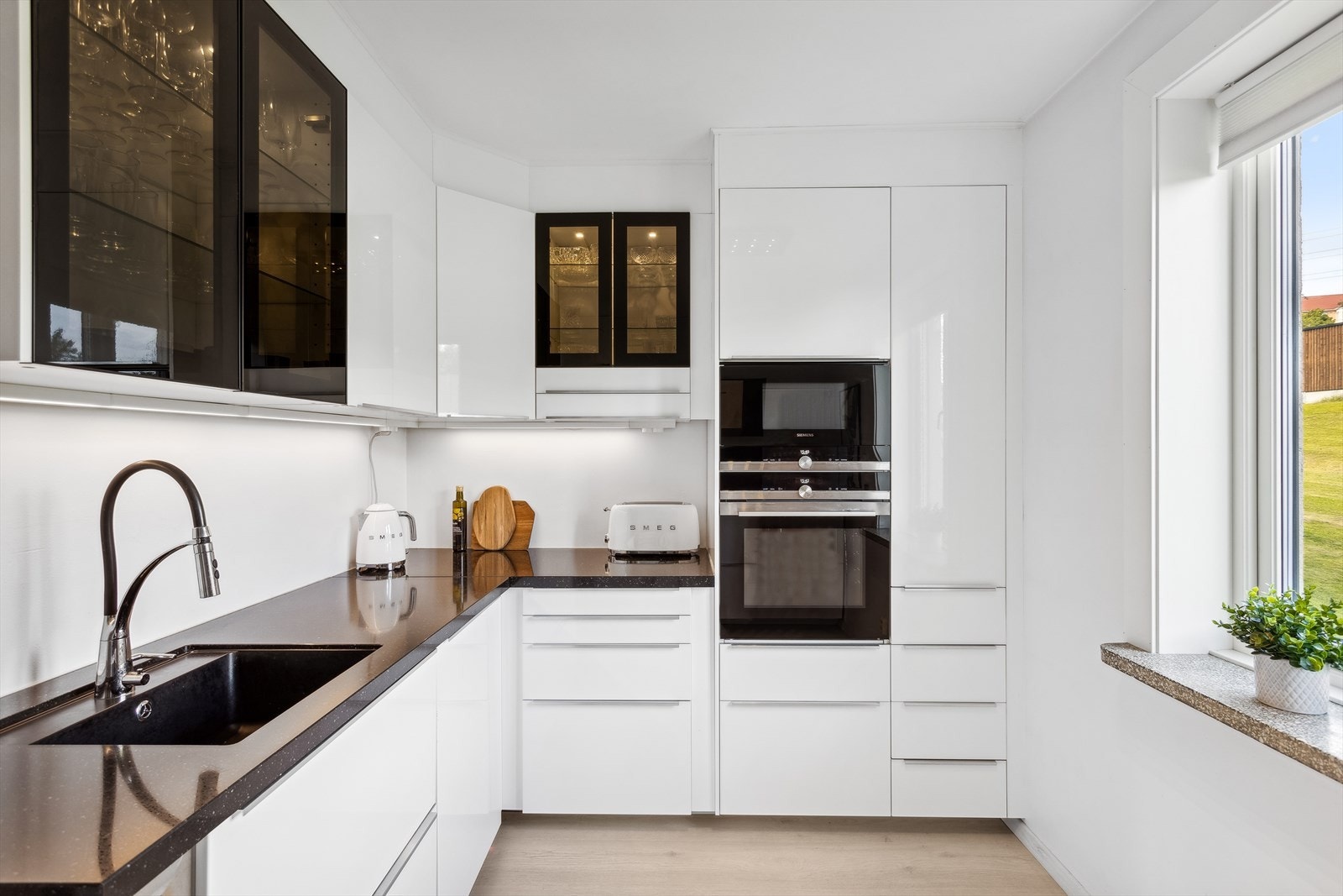 Lekker kjøkkeninnredning fra 2015 med hvite høyglans folierte fronter og benkeplater i stein med underlimt kum i kompositt Galleribilde