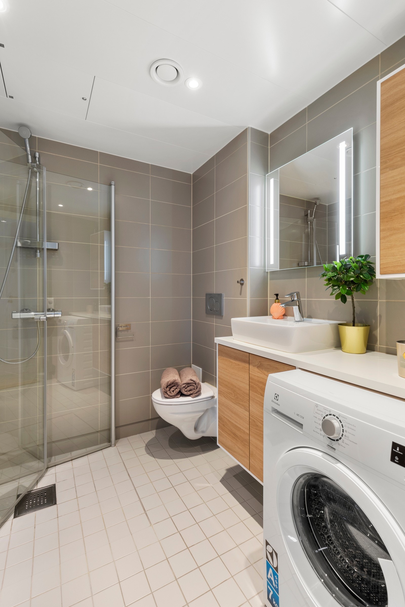 Badet har dusjnisje med plassbesparende, innfellbare glassdører og innebygget sisterne med vegghengt toalett. Galleribilde