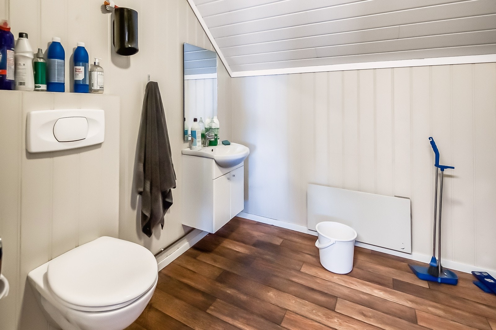 Bad innredet med belegg på gulv, vegghengt wc, servant med speil og underskap samt dusjkabinett Galleribilde