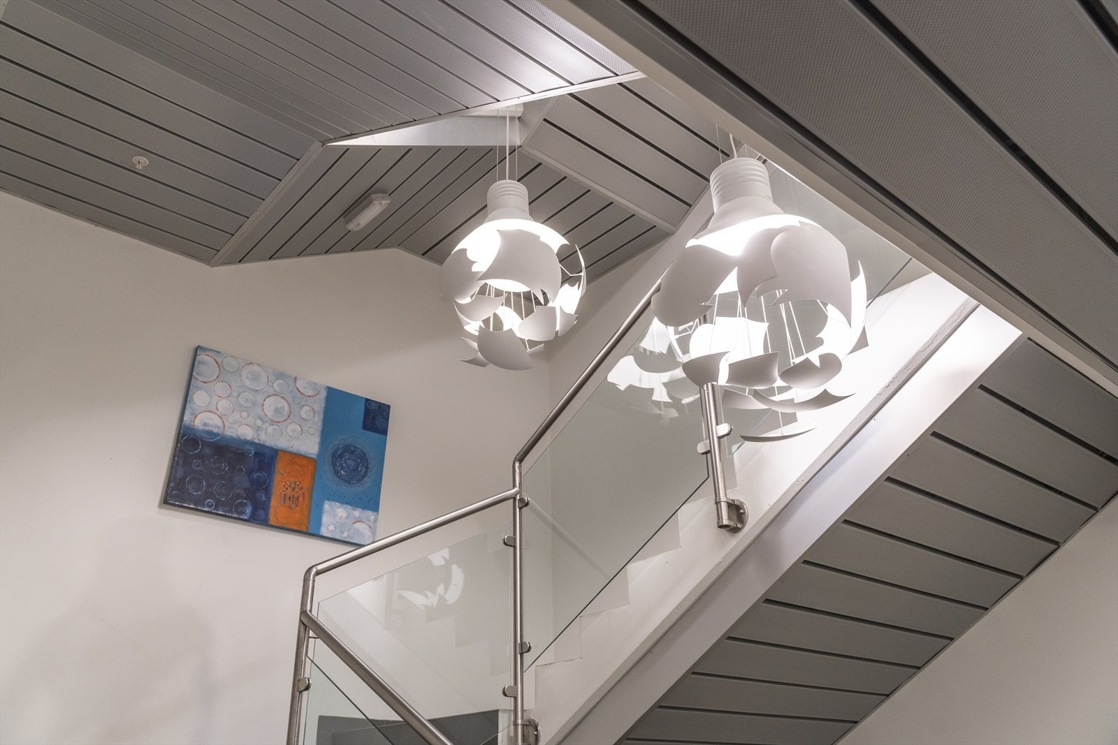 Moderne trappeoppgang med stilfulle belysningsdetaljer og elegant glassrekkverk, gir et lyst og luftig inntrykk. Galleribilde