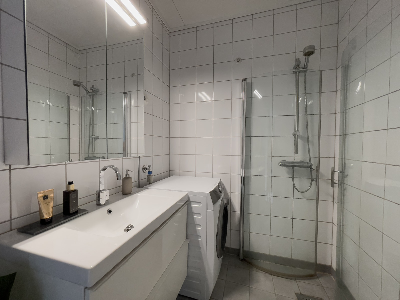 Lyst og fint bad med kombinert vaskemaskin og tørketrommel Galleribilde