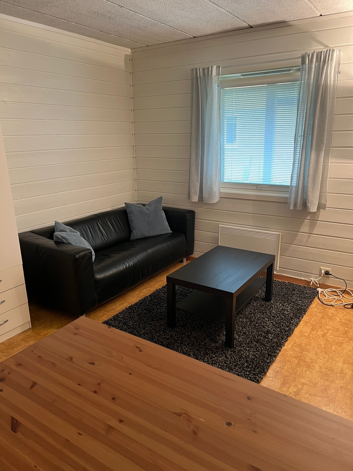 Utleid. Hybel nr. 3. 16,5 kvm. Sofa, sofabord og stort vindu som gir mye dagslys. Galleribilde