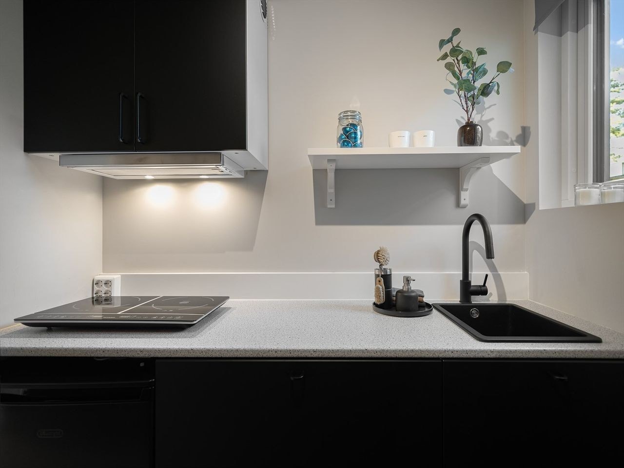 Kjøkken med kokeplate, kjøleskap og frittstående ovn. Galleribilde