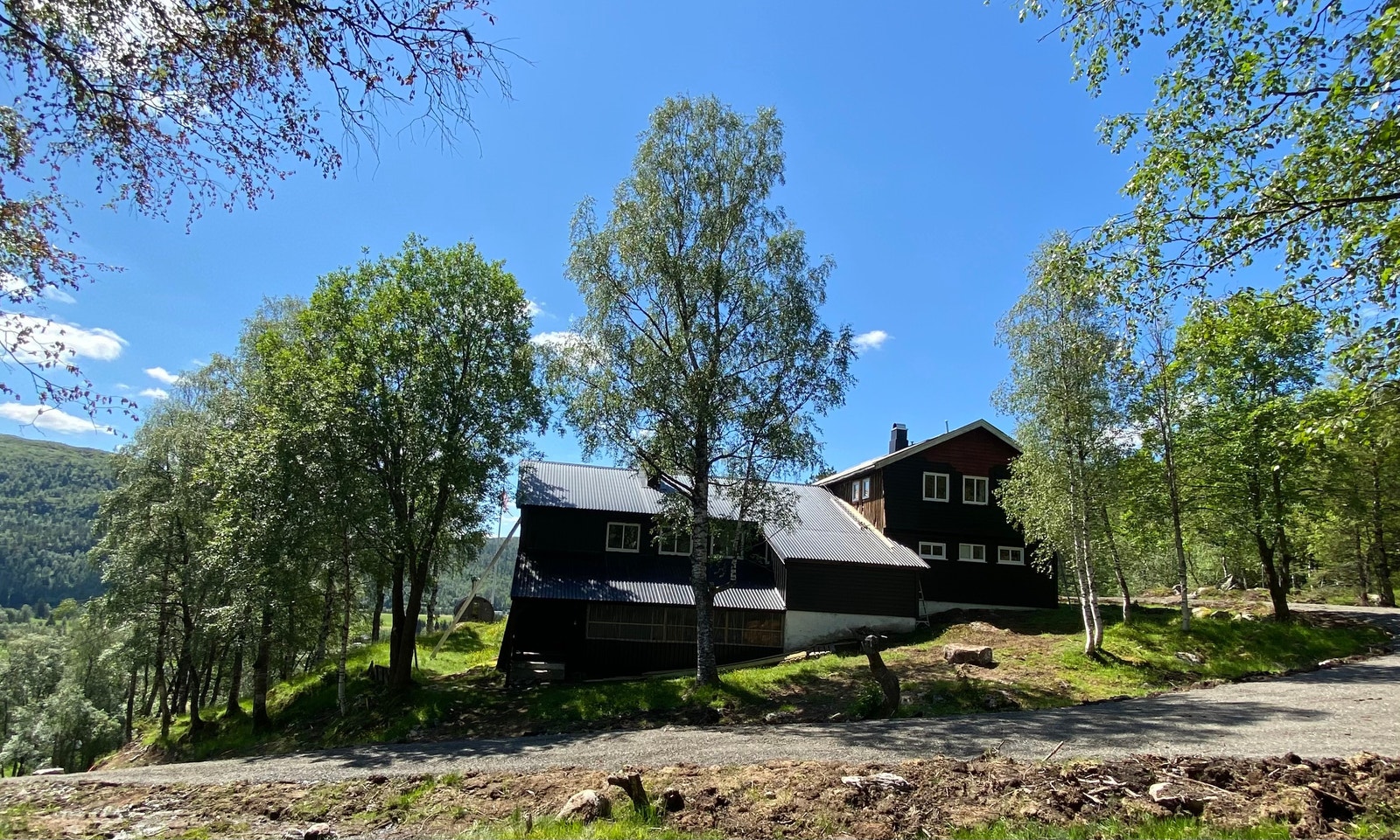 Baksiden av hytta hvor du ser litt av traktorvei/sommervei opp til hytta. Galleribilde