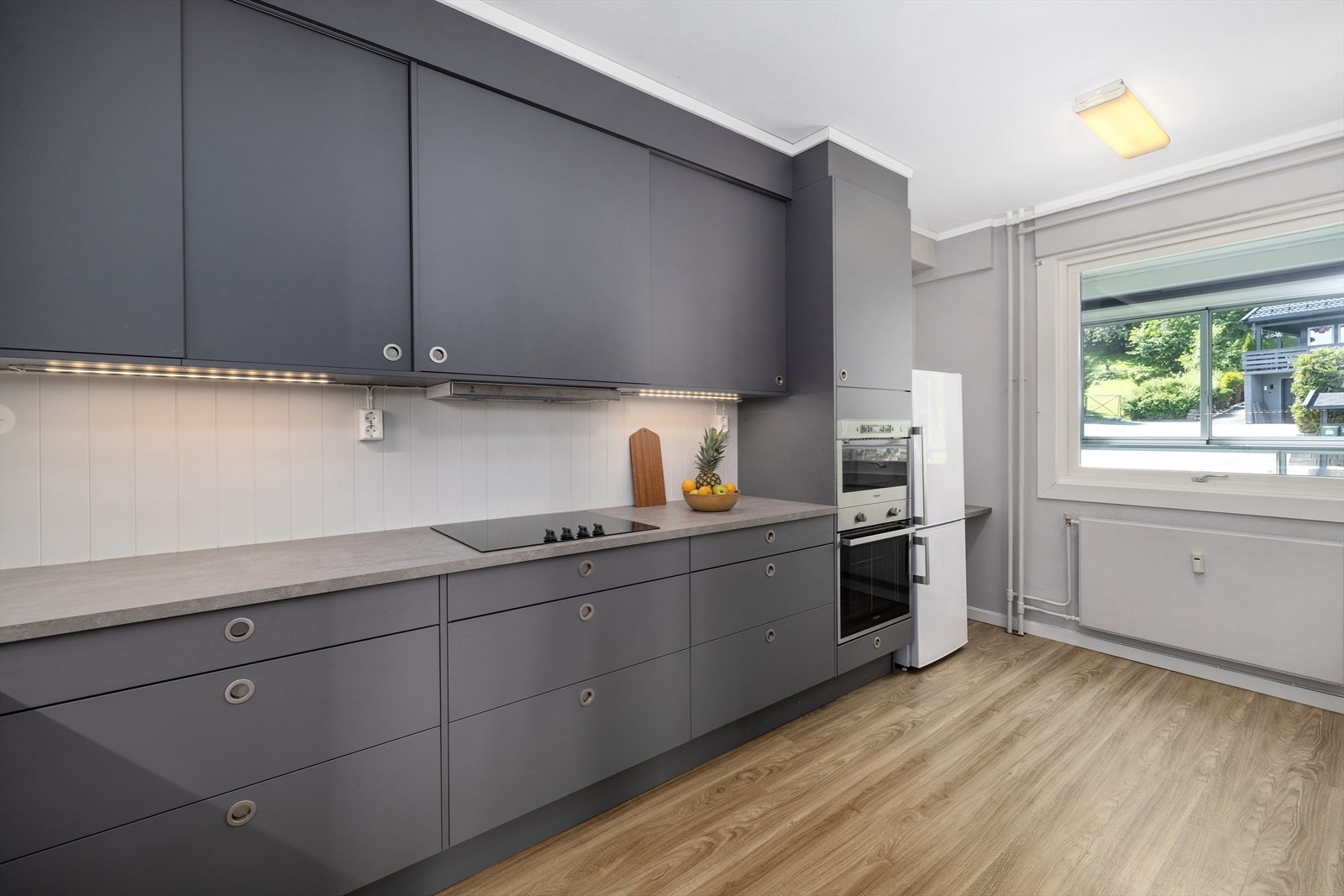 Leiligheten har innholdsrik kjøkkeninnredning med takhøye skap. Galleribilde