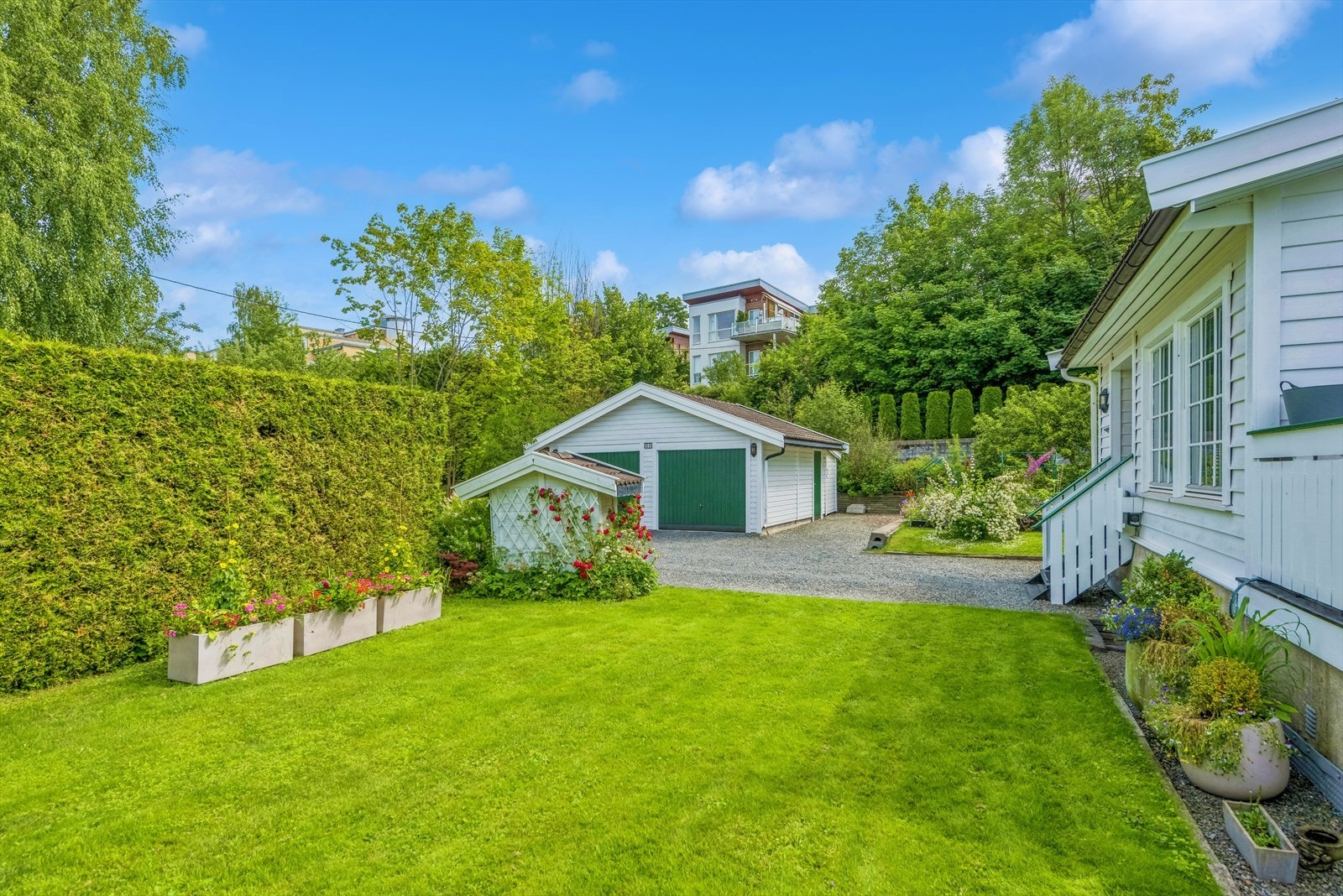 Hagen er pent opparbeidet med plen, busker og blomster Galleribilde