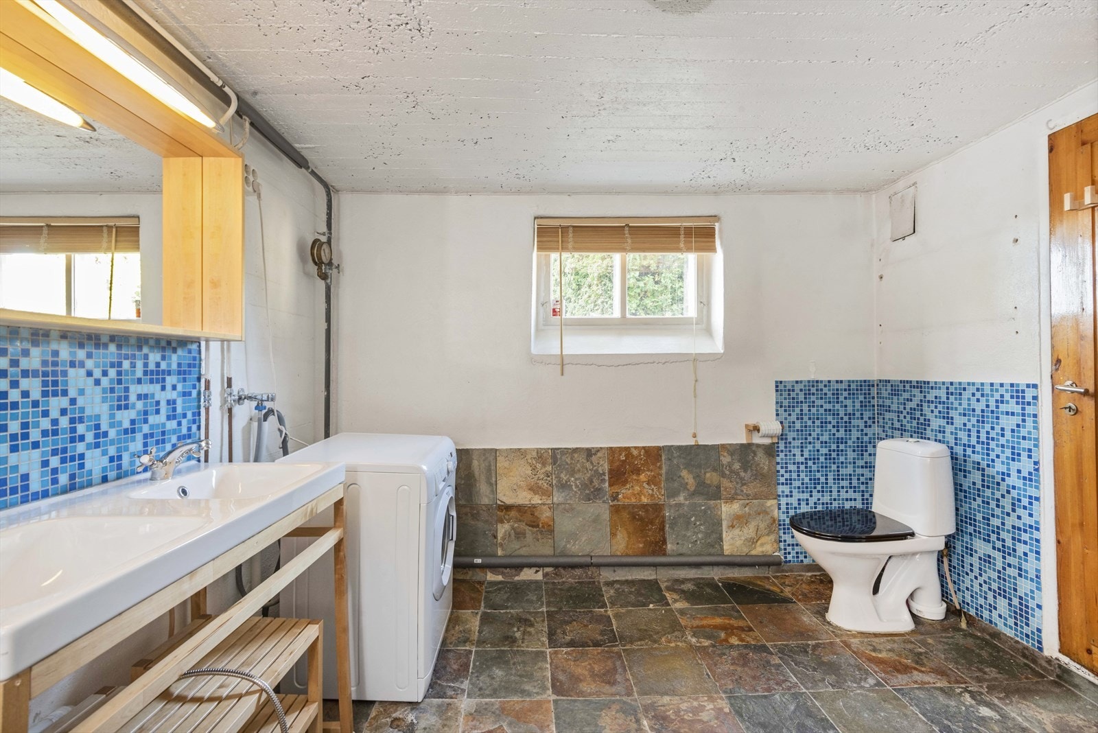 Bad/vaskerom i underetasjen med to nedfelte servanter, dusjnisje og opplegg for vaskemaskin og tørketrommel. Galleribilde