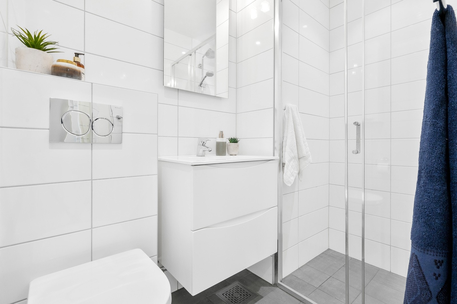 Badet er utstyrt med dusjsone med skyvedører av glass og metall, samt hånddusj og regnfallsdusj. Galleribilde