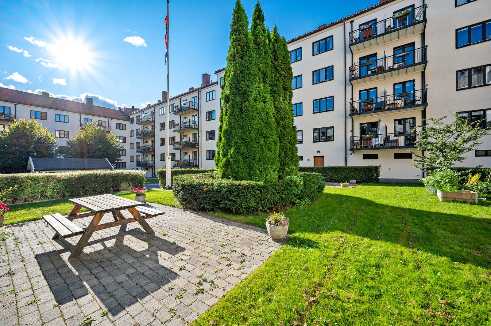 Bakgården er pent opparbeidet med sitteplasser, fine blomster, busker og trær. Galleribilde