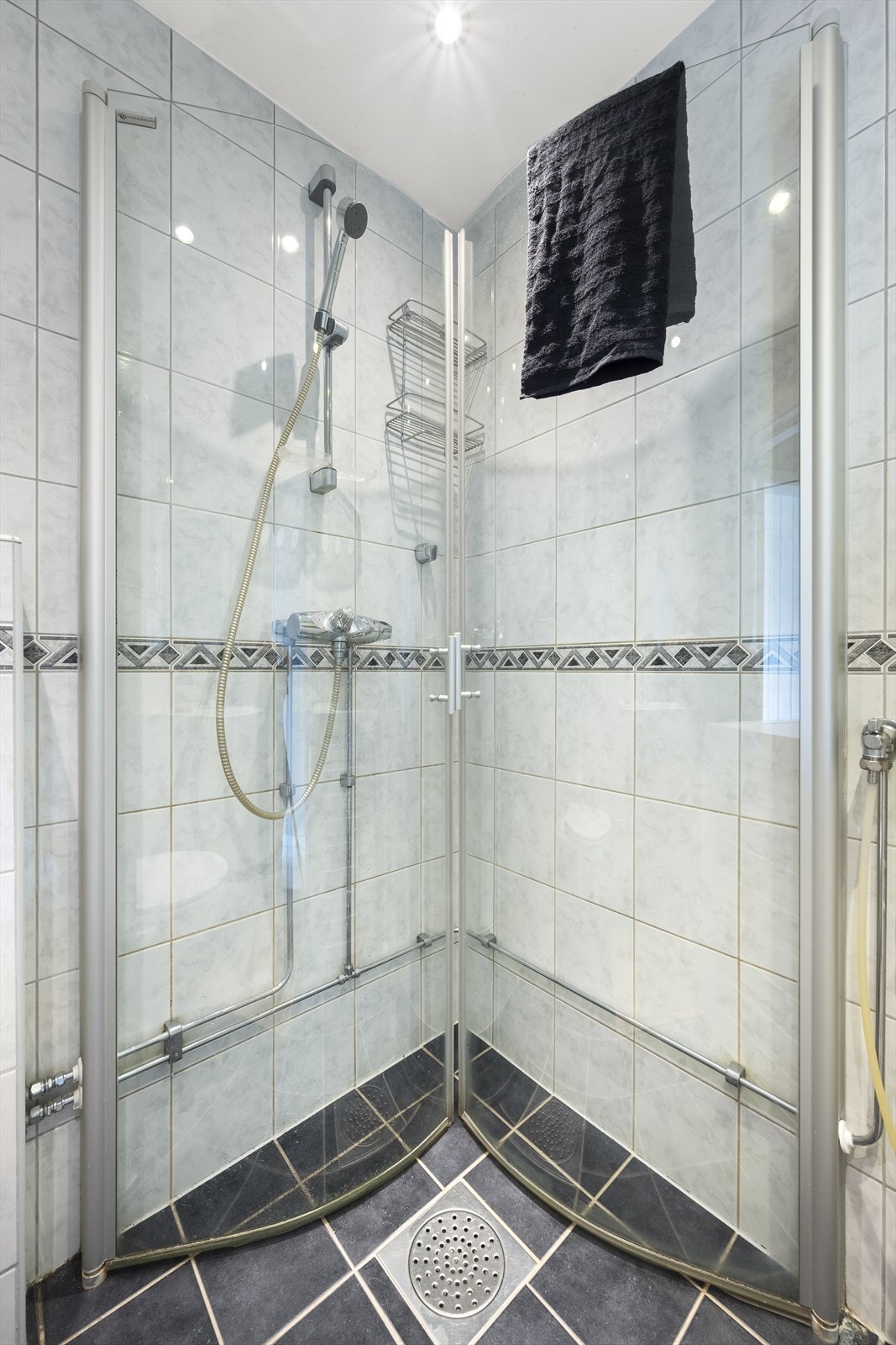 Badet har praktisk dusjhjørne med innfellbare dører, servant med oppbevaring, vegghengt toalett og medfølgende vaskemaskin Galleribilde