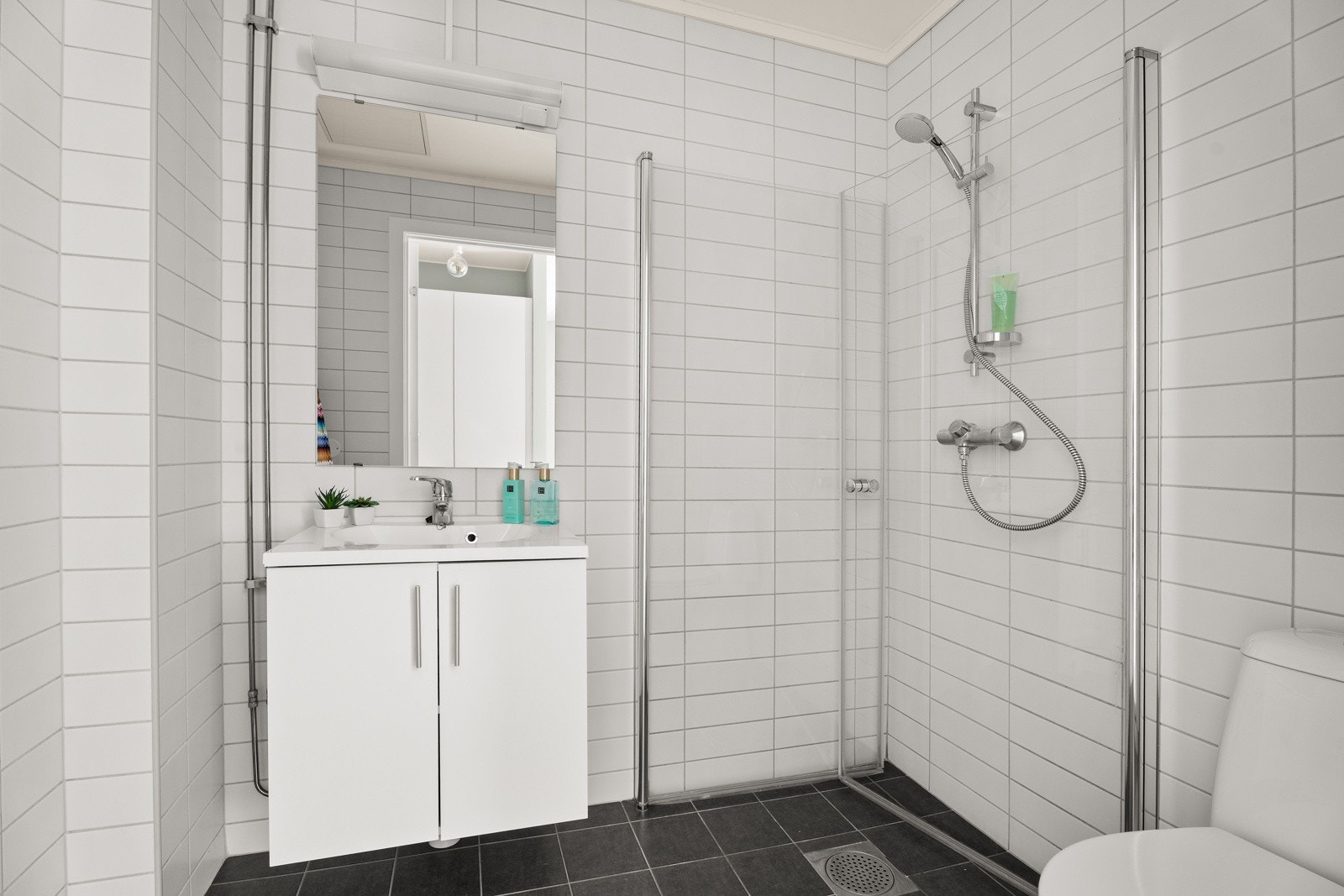 Lyst og moderne bad, nytt fra 2014, med dusjhjørne med glassdører, stilfull baderomsinnredning med heldekkende servant og WC. Galleribilde