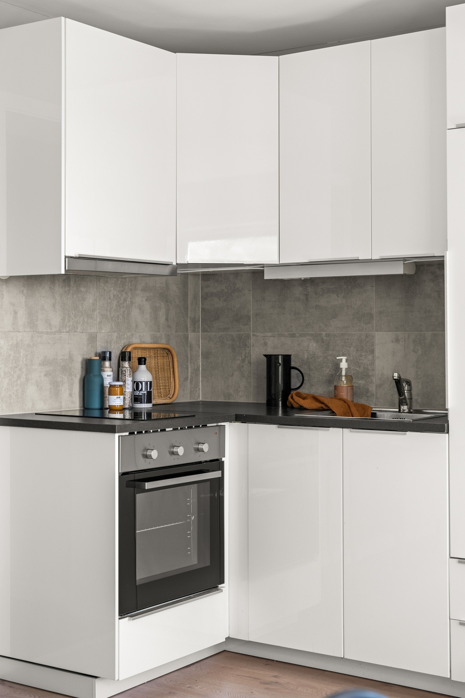 Moderne kjøkkeninnredning fra Ikea med hvite glatte fronter og laminert benkeplate med nedfelt oppvaskkum. Både fint og praktisk med fliser i benkeryggen og belysning under overskap. Galleribilde