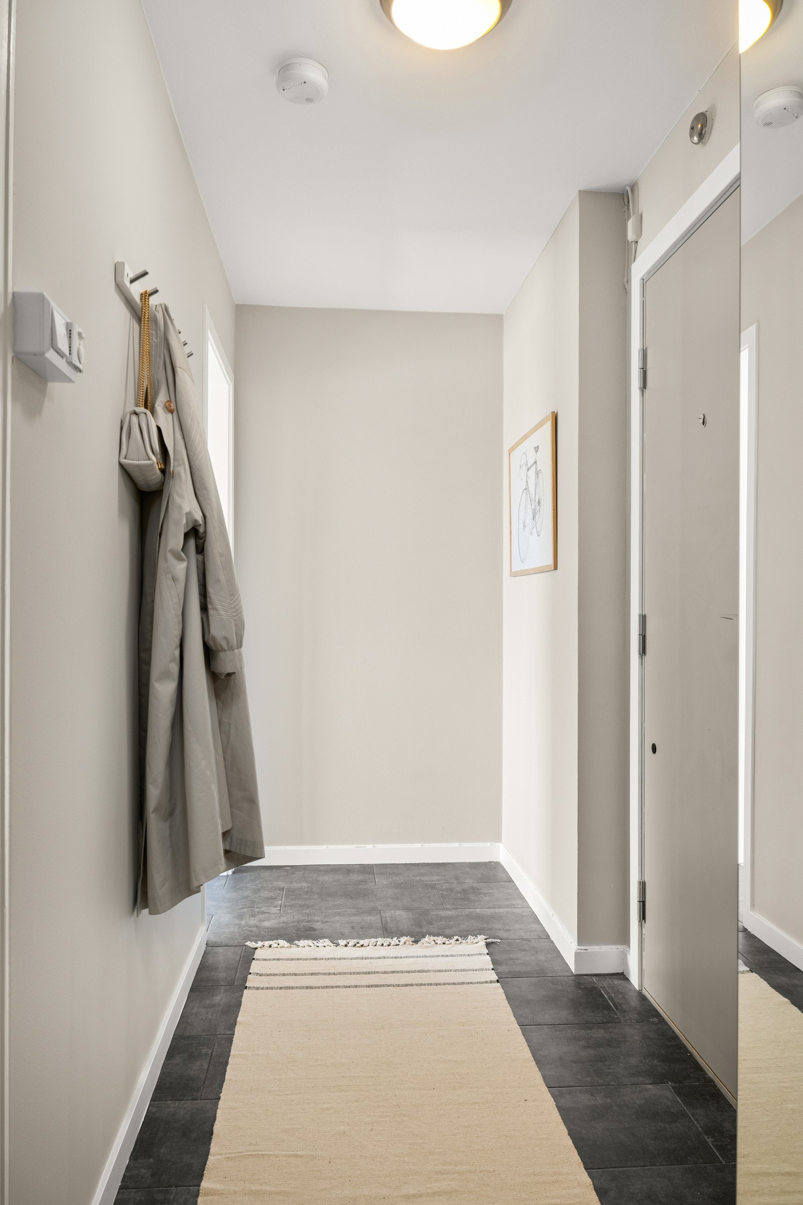 Du tar deg opp til leiligheten i byggets 8. etasje via felles trapperom med heis. Når du entrer leiligheten kommer du inn i en lys og praktisk entré med flislagt gulv. Galleribilde