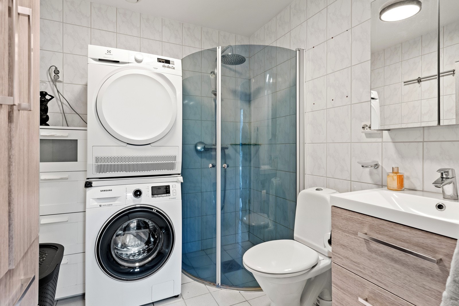 Romslig, flislagt baderom med gulvvarme, dusjhjørne og opplegg til vaskemaskin og tørketrommel. Galleribilde