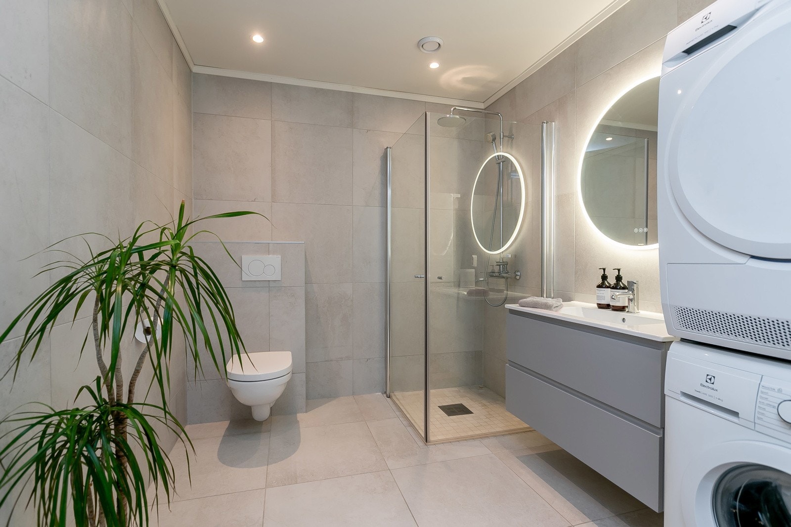 Badet er romslig med dusjsone, vegghengt toalett, bred servant og opplegg for vaskemaskin og tørketrommel Galleribilde