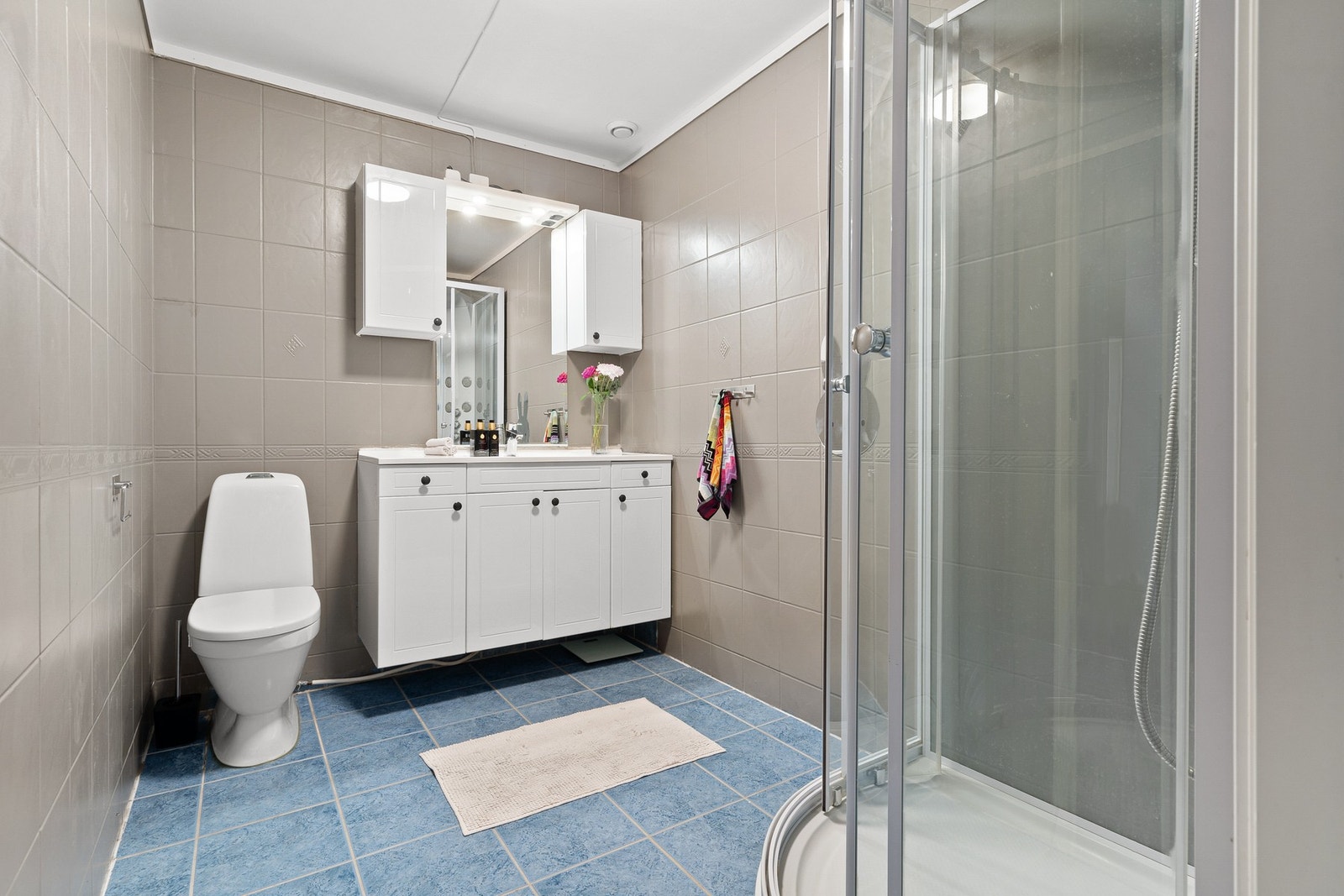 Flislagt baderom med toalett fra 2020, lys baderomsinnredning og dusjkabinett. Galleribilde