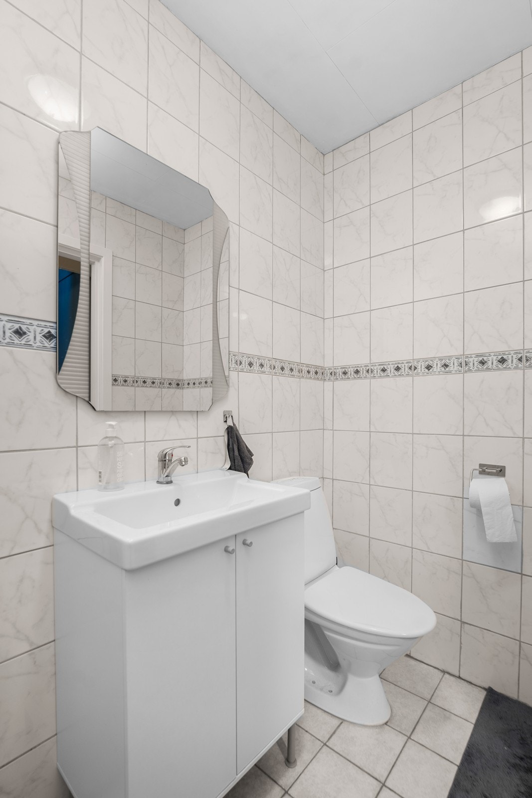 Bad i underetasje har eldre overflater. Her er fliser på vegger og gulv hvor gulvet har elektriske varmekabler. Galleribilde