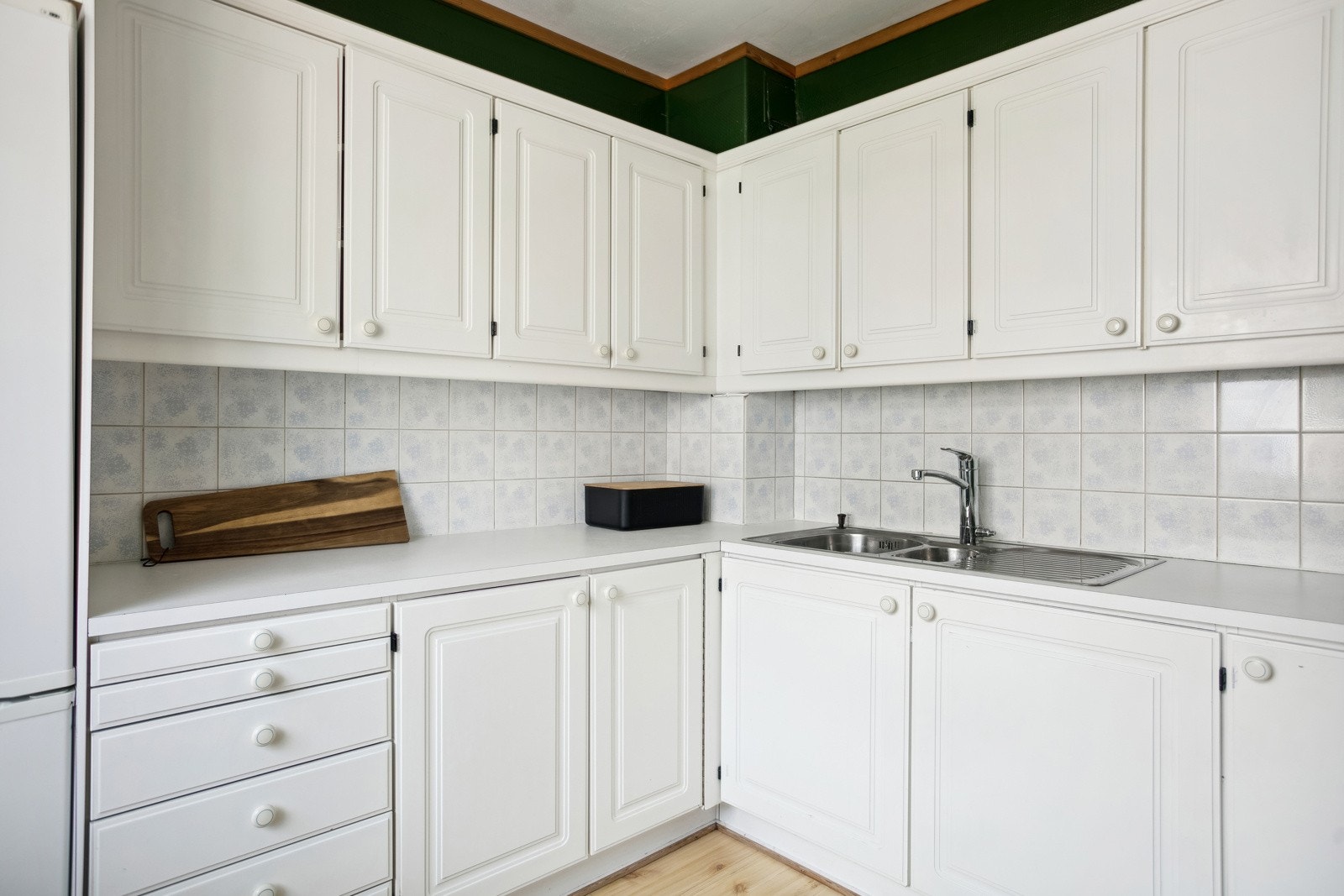 Kjøkkeninnredning med ett-speils lakkerte skapfronter, laminat benkeplate med fliser på bakvegg, 1 1/2 oppvaskkum med benkebeslag, ventilator. Galleribilde