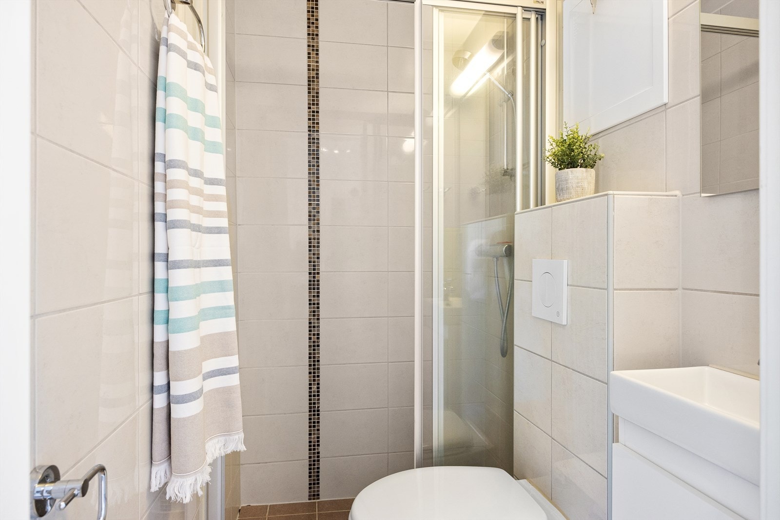 Badet består av veggmontert wc, dusjplass og servant med ettgreps blandebatteri i innredning. Galleribilde