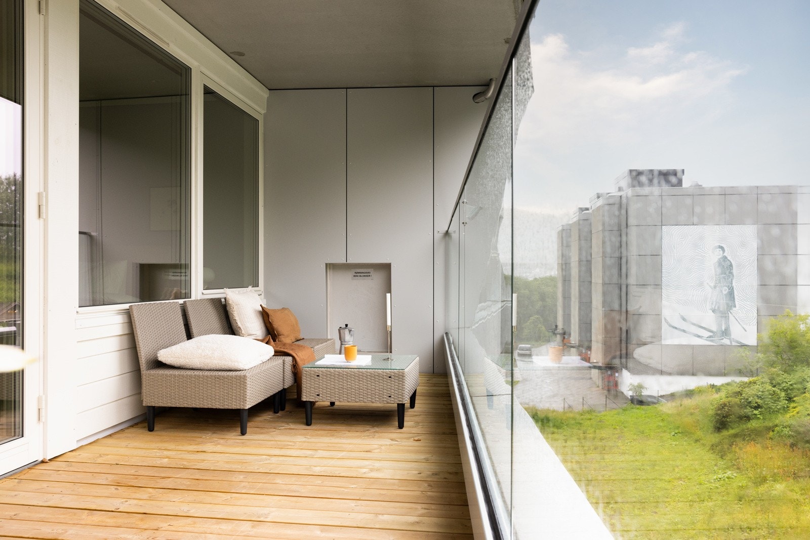 Balkongen er bekledd med terrassebord og har rekkverk av glass og stål. Galleribilde