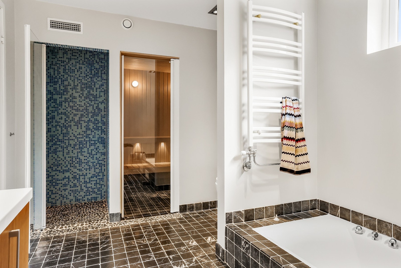 Badet har dusjnisje med glassdør, badekar og badstue. Galleribilde